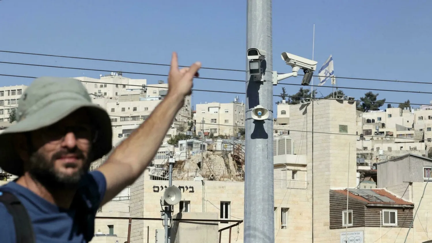 A man points at surveillance cameras in the Palestinian city of Hebron, where an organization working with former soldiers says facial recognition technology is targeting Palestinians. (AFP)