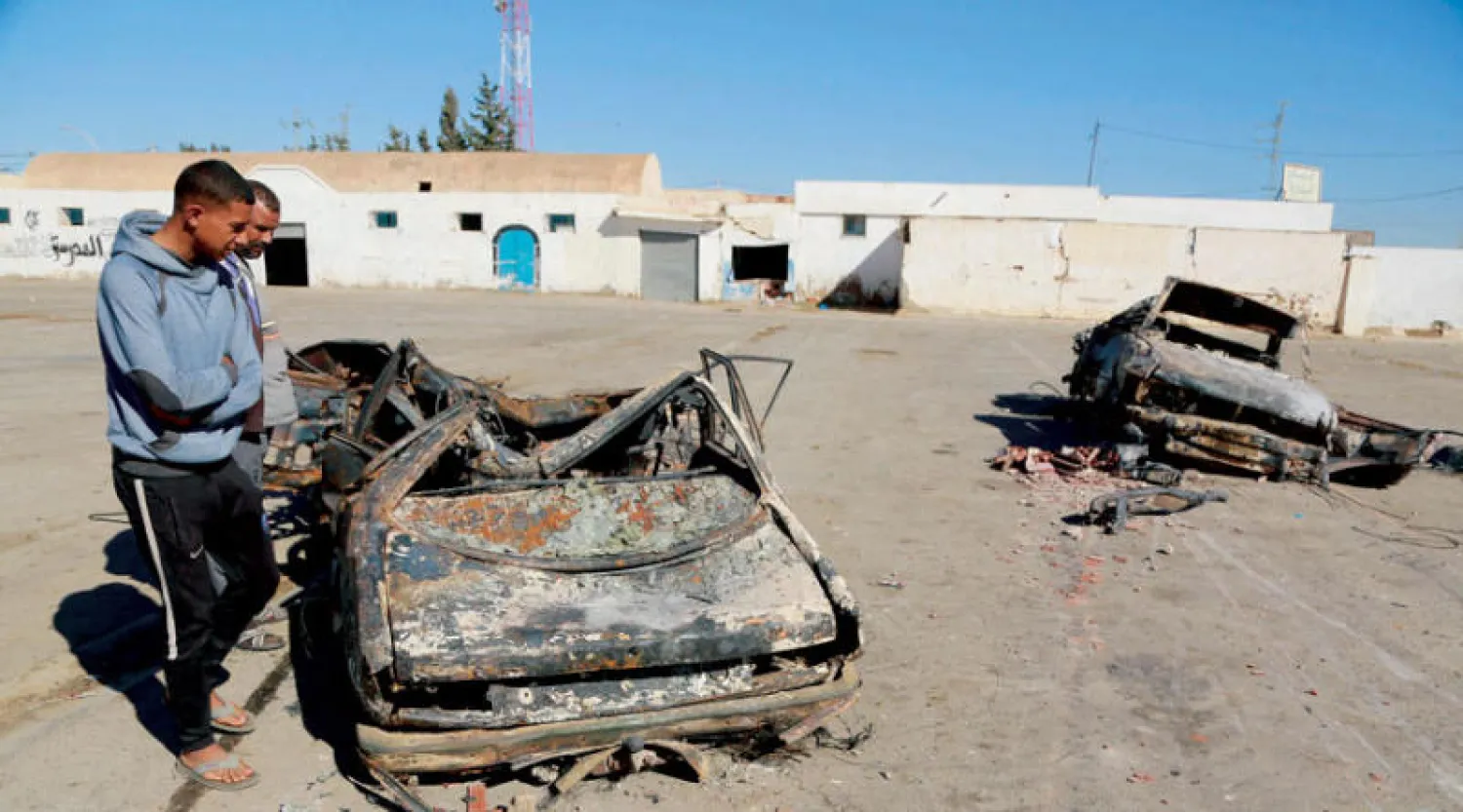 تونسي يعاين سيارة تم حرقها خلال احتجاجات سكان مدينة عقارب على السلطات (أ.ف.ب)