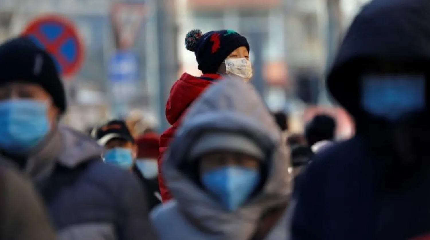 FILE PHOTO: People wearing masks walk in a street in Beijing?s central business district (CBD) during morning rush hour, following the coronavirus disease (COVID-19) outbreak, in China December 8, 2020. REUTERS/Tingshu Wang/File Photo

