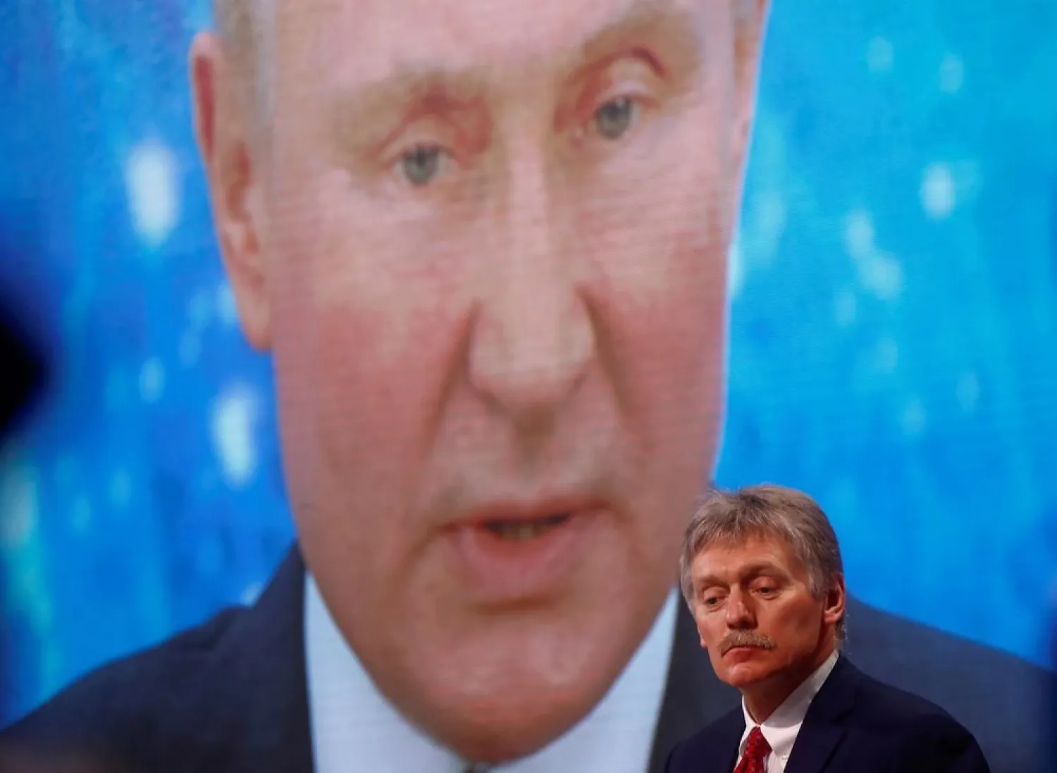 Kremlin spokesman Dmitry Peskov sits in front of an electronic screen featuring Russian President Vladimir Putin in Moscow, Russia December 17, 2020. (Reuters)