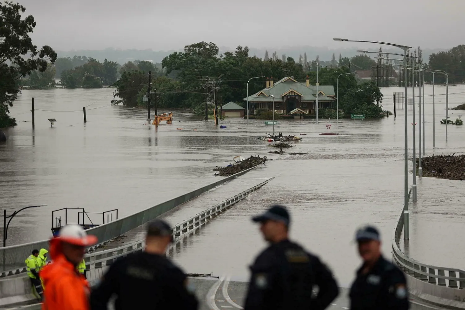 Police officers and road workers are seen in front of a submerged structure visible in floodwaters in the suburb of Windsor as the state of New South Wales experiences widespread flooding and severe weather, in Sydney, Australia, March 22, 2021. (Reuters)