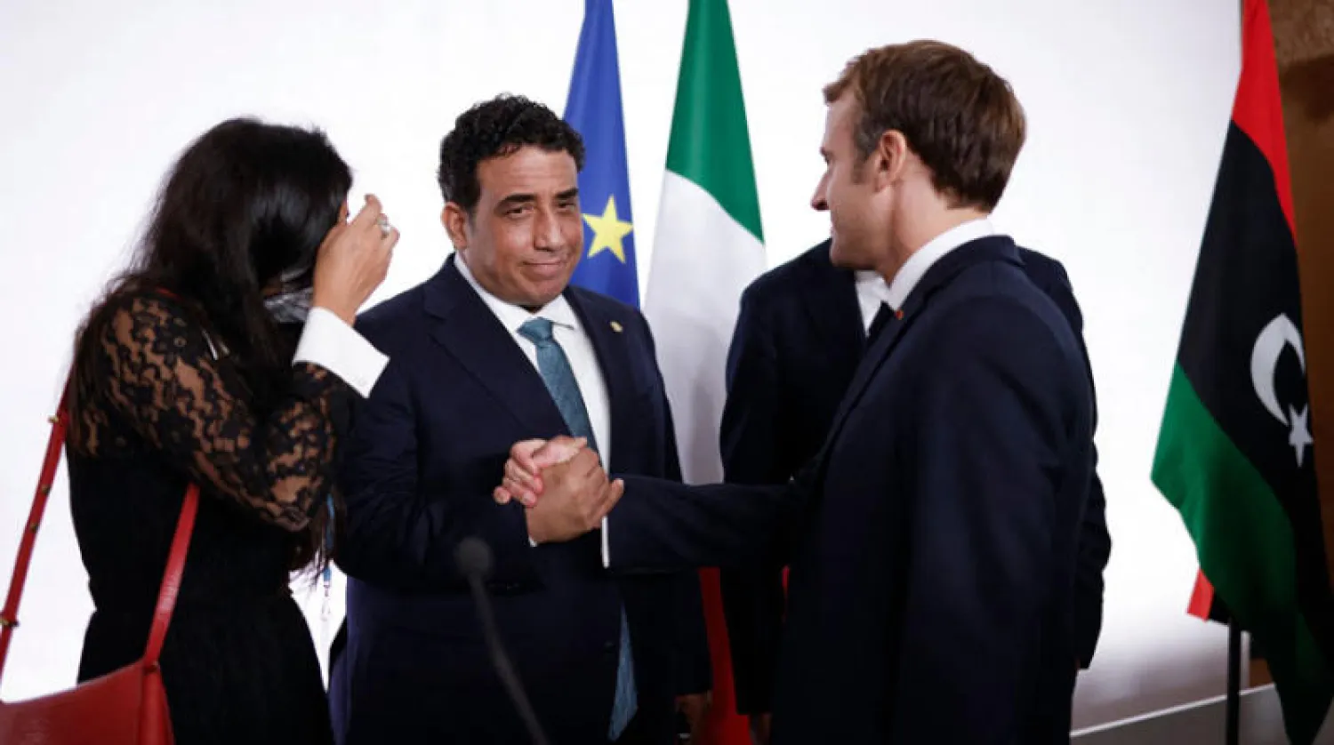 الرئيس الفرنسي مصافحاً محمد المنفي خلال مشاركته في مؤتمر باريس حول ليبيا أول من أمس (أ.ف.ب)