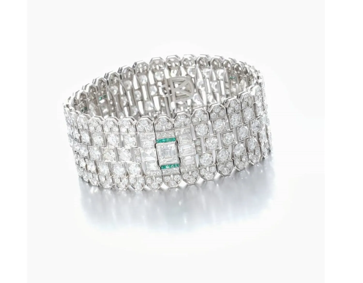 The bracelet is a collet-set with marquise-shaped, square and baguette diamonds, enhanced with circular-cut diamonds, further embellished with caliber-cut emeralds.  (Sotheby's)