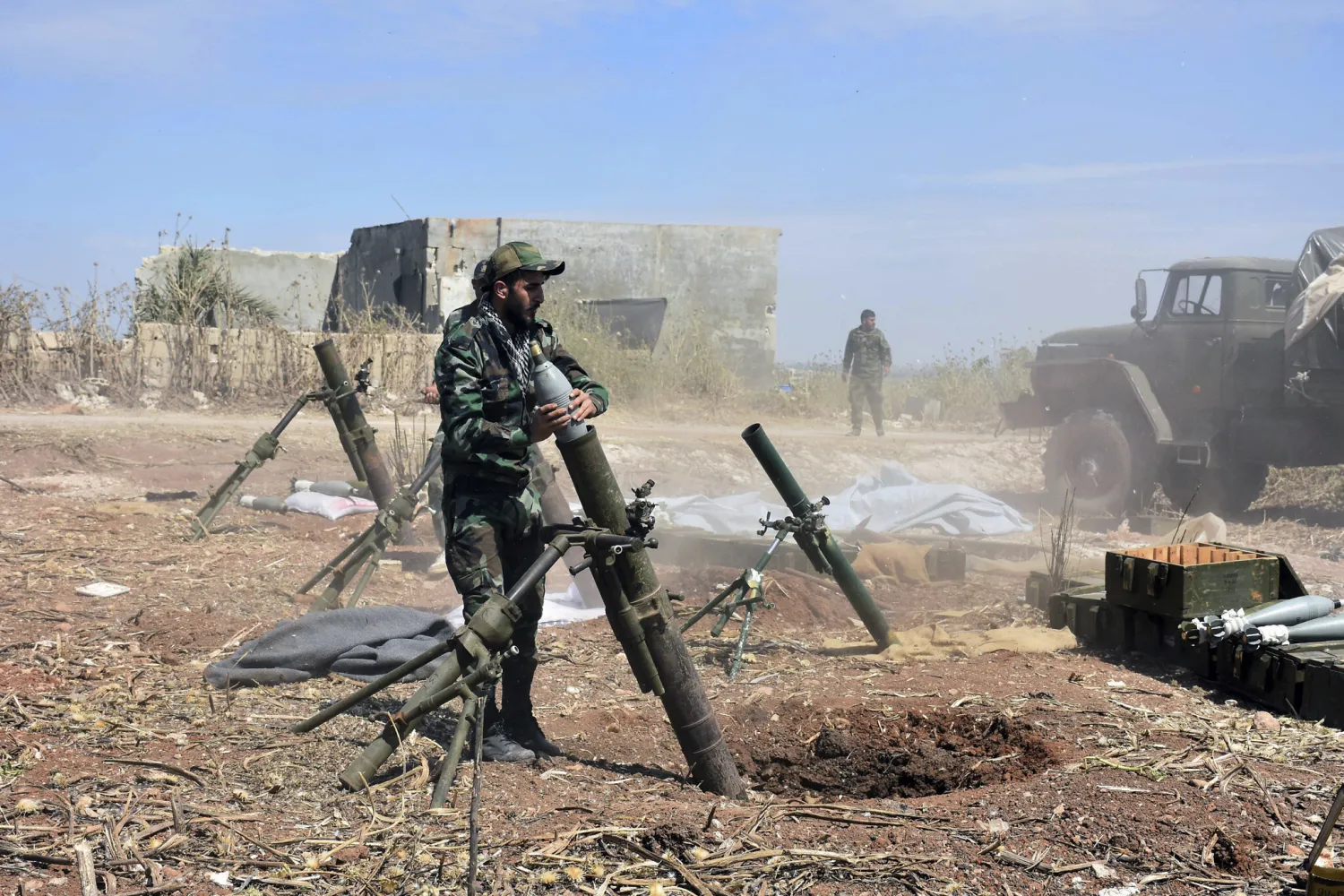 Syrian army soldiers prepare to launch a mortar in the village of Kfar Nabuda, in the countryside of Hama province on May 11, 2019. (SANA via AP)