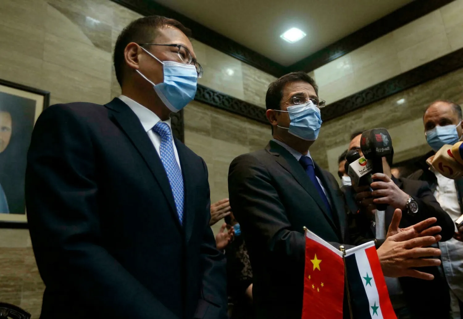 Syrian Health Minister Hassan al-Ghabash (R) and Chinese ambassador Feng Biao (L) take part in a ceremony upon the arrival of Sinopharm Covid-19 vaccine doses, in the capital Damascus. (AFP)