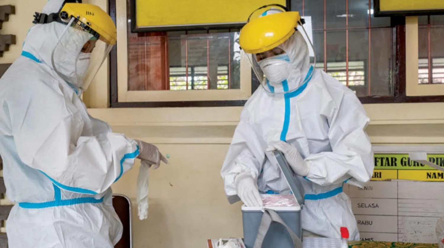 موظف رعاية صحية يجمع اختبارات مسحة الأنف من معلمي المدارس الابتدائية قبل بدء التعليم وجهاً لوجه في بالي إندونيسيا أمس (إ.ب.أ)