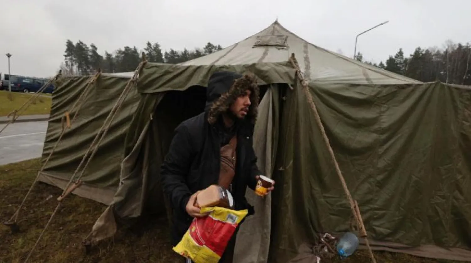 Bir adam Belarus-Polonya sınırındaki bir kampta Belarus askerleri tarafından sağlanan yiyecekleri taşıyor (EPA)