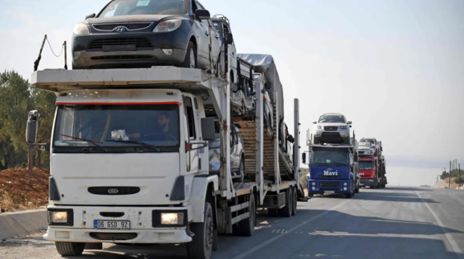 شاحنات تحمل سيارات مستوردة للبيع شمال غربي سوريا أول من أمس (أ.ف.ب)
