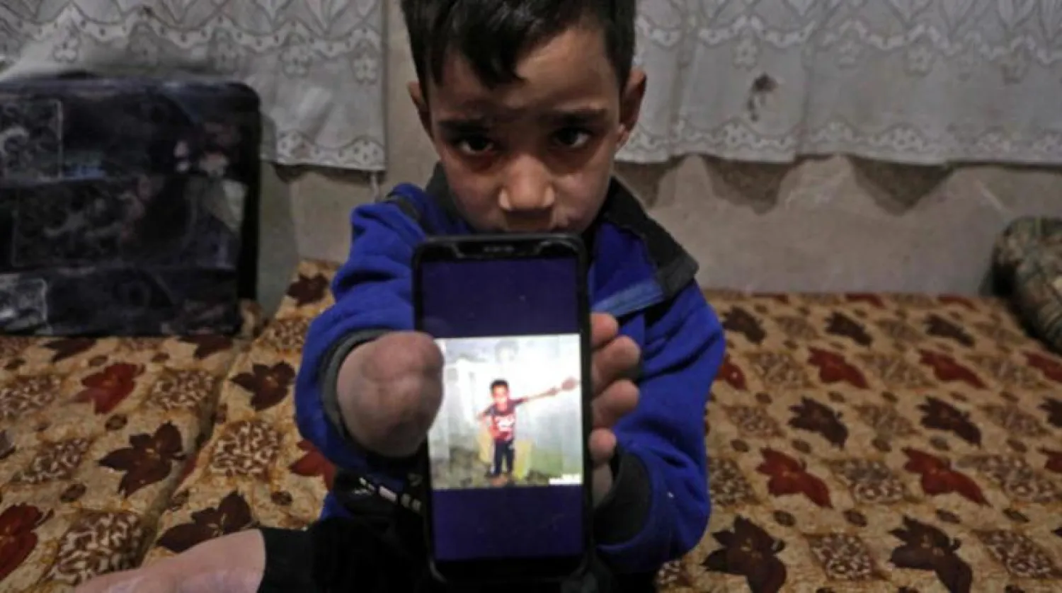 Syrian boy displays a photo of himself back at his home in northern Syria (File/AFP)