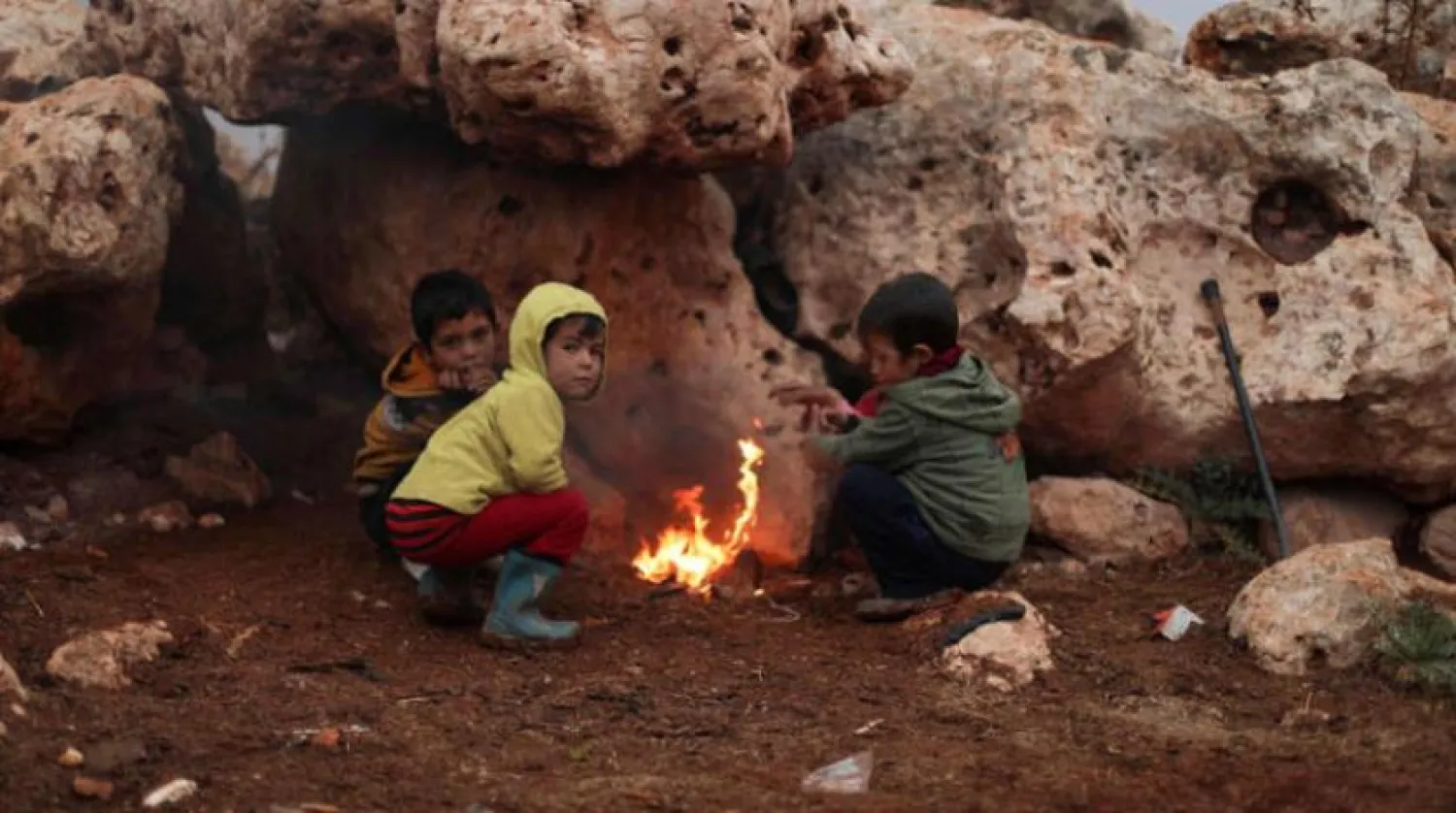 
تعدادی از کودکان روز گذشته مصادف با روز جهانی حقوق کودک، خود را در یک کمپ برای آوارگان در روستای دانا در استان ادلب در شمال غرب سوریه گرم می‌کنند (AFP)
