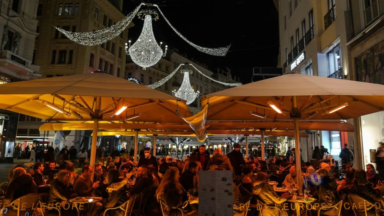 People sit at an outdoor café on a street decorated with Christmas lights in Vienna, Austria, Saturday, Nov. 20, 2021. (AP Photo/Vadim Ghirda)