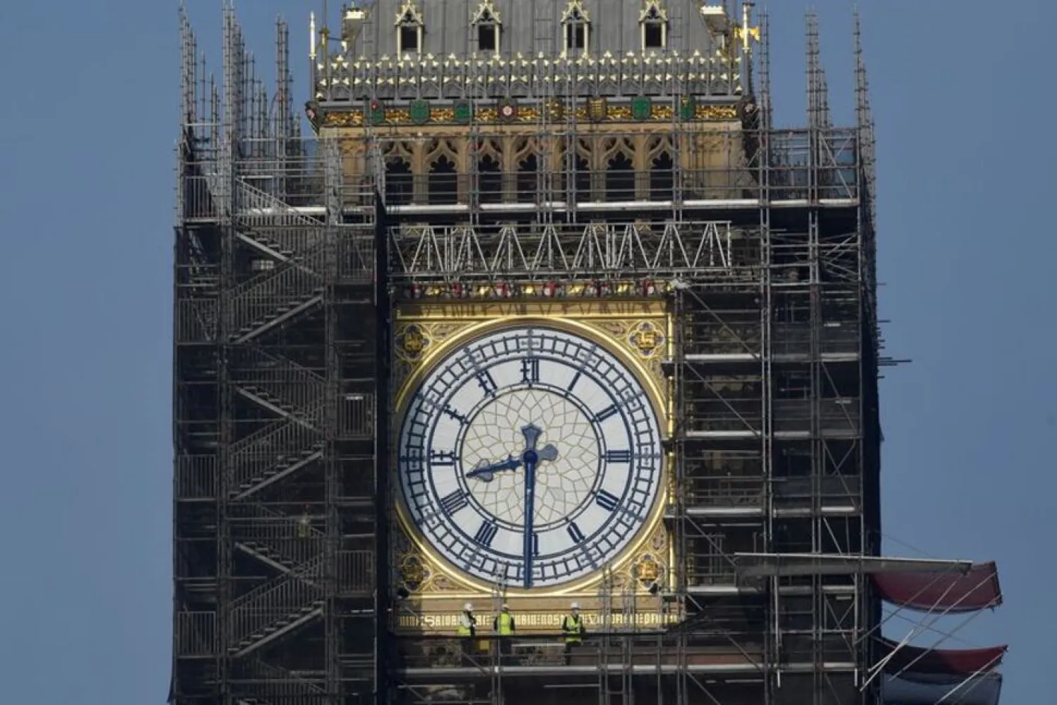 Workers stand on scaffolding underneath one of the clock faces on the Elizabeth Tower, more commonly known as Big Ben, as hands and dials are seen restored to the original Prussian blue colouring, whilst renovation works continue at the Houses of Parliament, London, Britain, September 6, 2021. (Reuters)