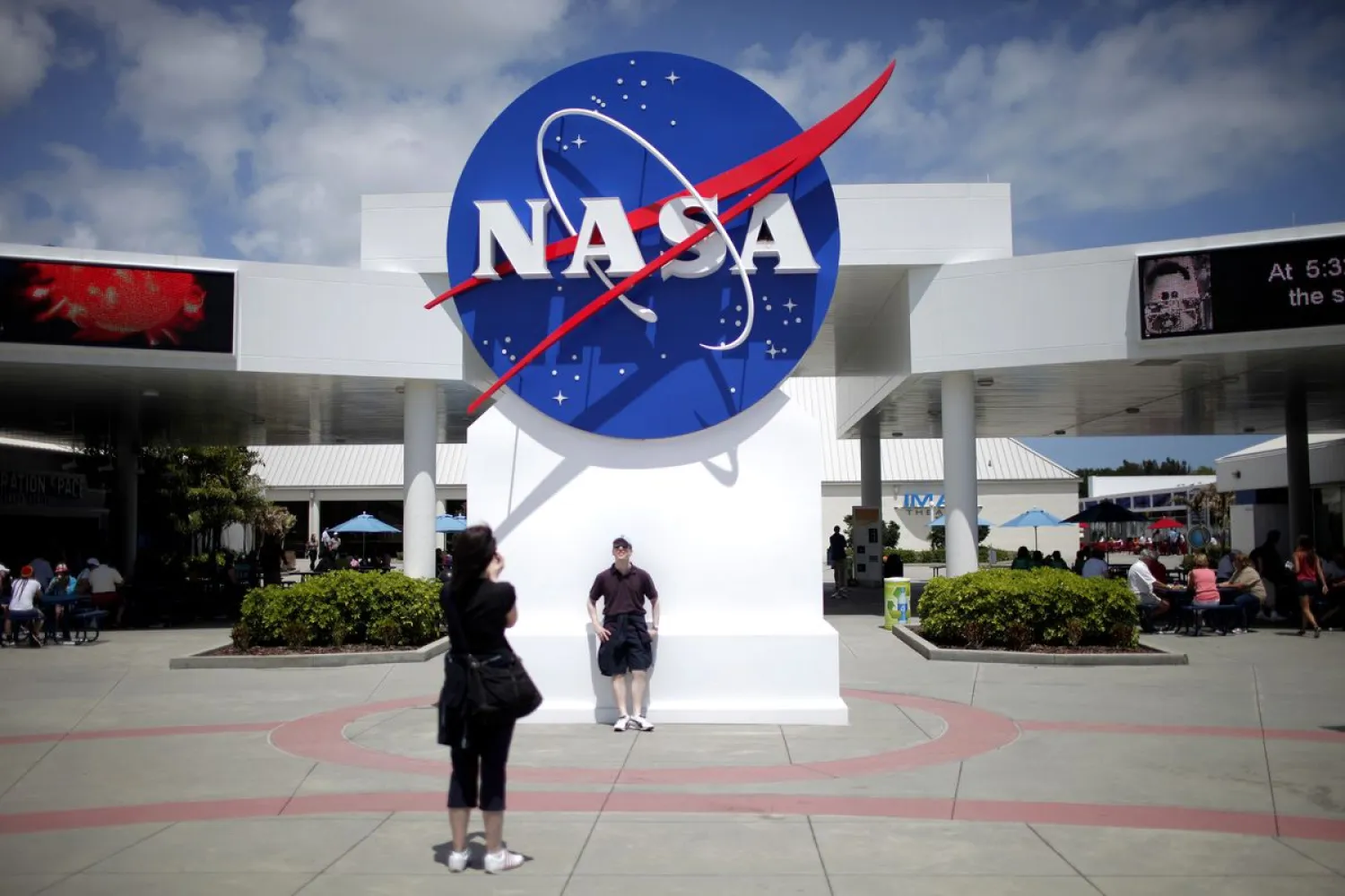 Tourists take pictures of a NASA sign at the Kennedy Space Center visitors complex in Cape Canaveral, Florida April 14, 2010. REUTERS/Carlos Barria