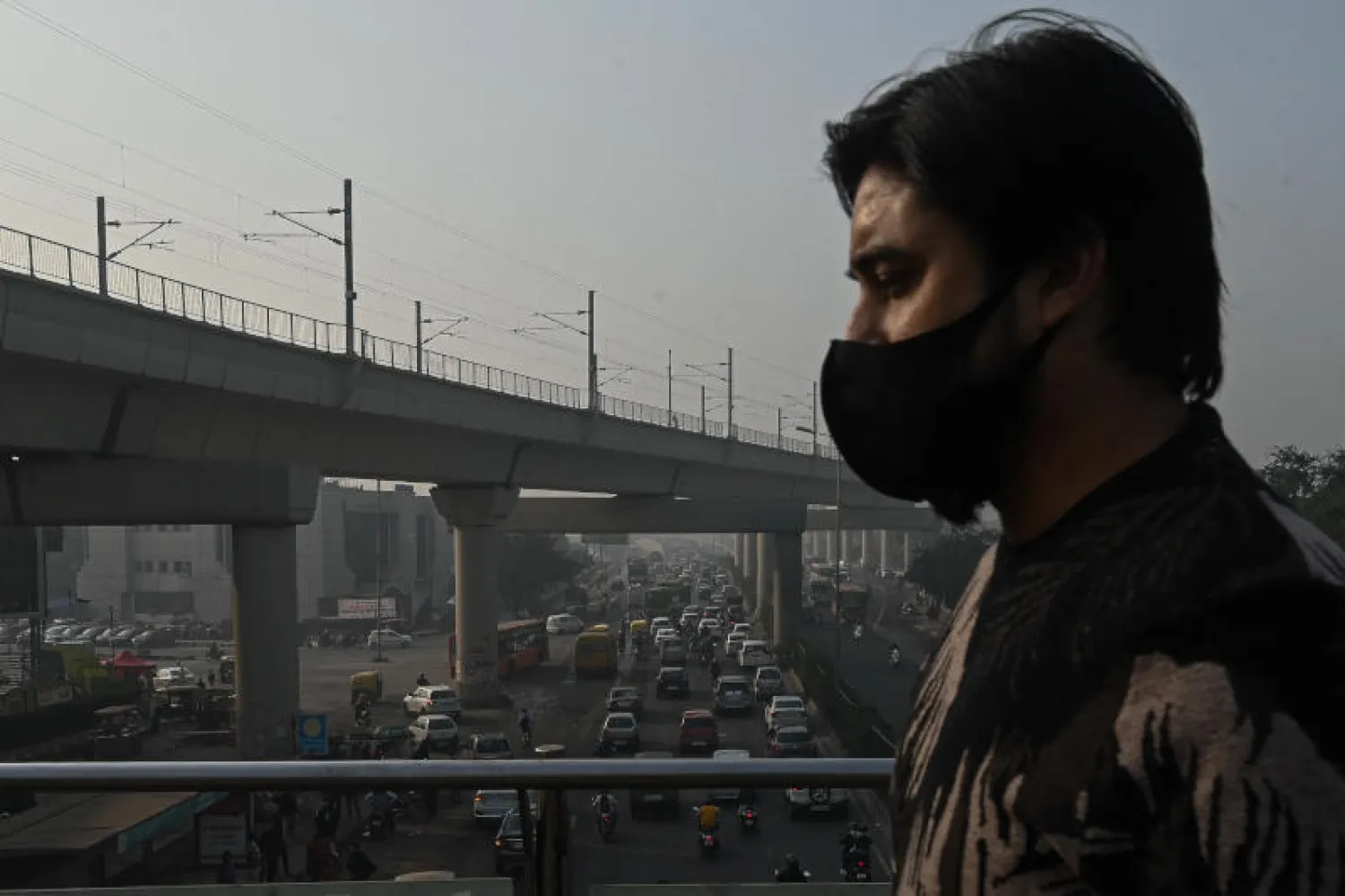 رجل يرتدي القناع الواقي خلال تجوله في أحد شوراع نيودلهي وسط الغبار الناجم عن التلوث (أ.ف.ب)