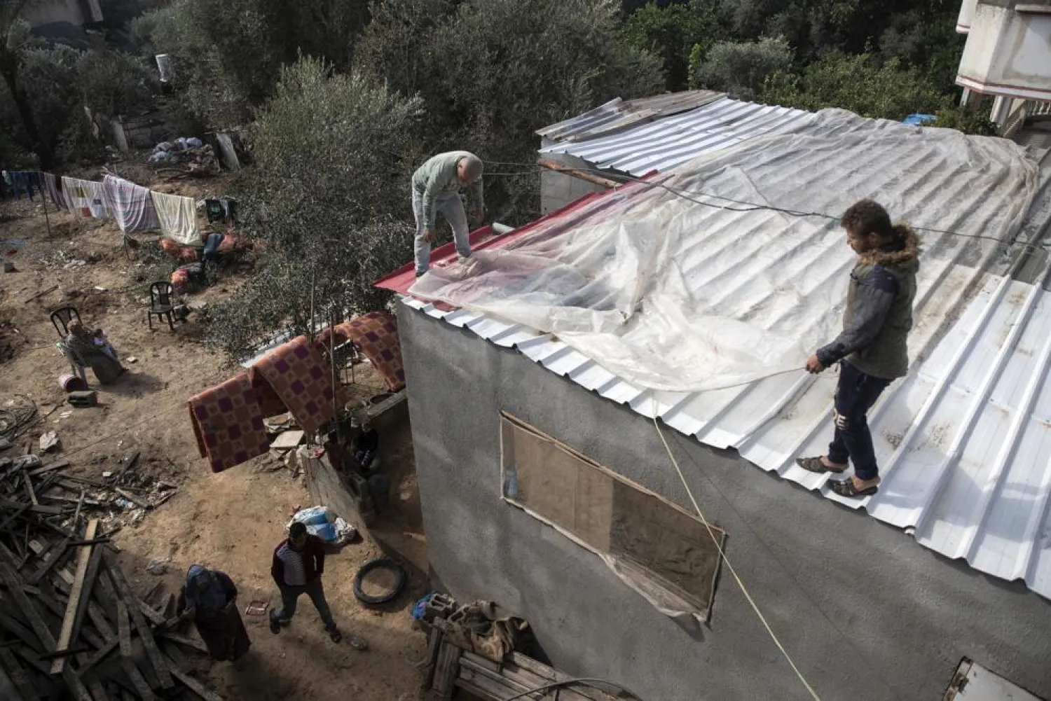 Palestinians cover the roof of their house with nylon to protect it from rain leaks after it was damaged during the 11-day Gaza war in May 2021, in the town of Beit Lahiya, northern Gaza Strip, Monday, Nov. 21, 2021. (AP Photo/Khalil Hamra)
