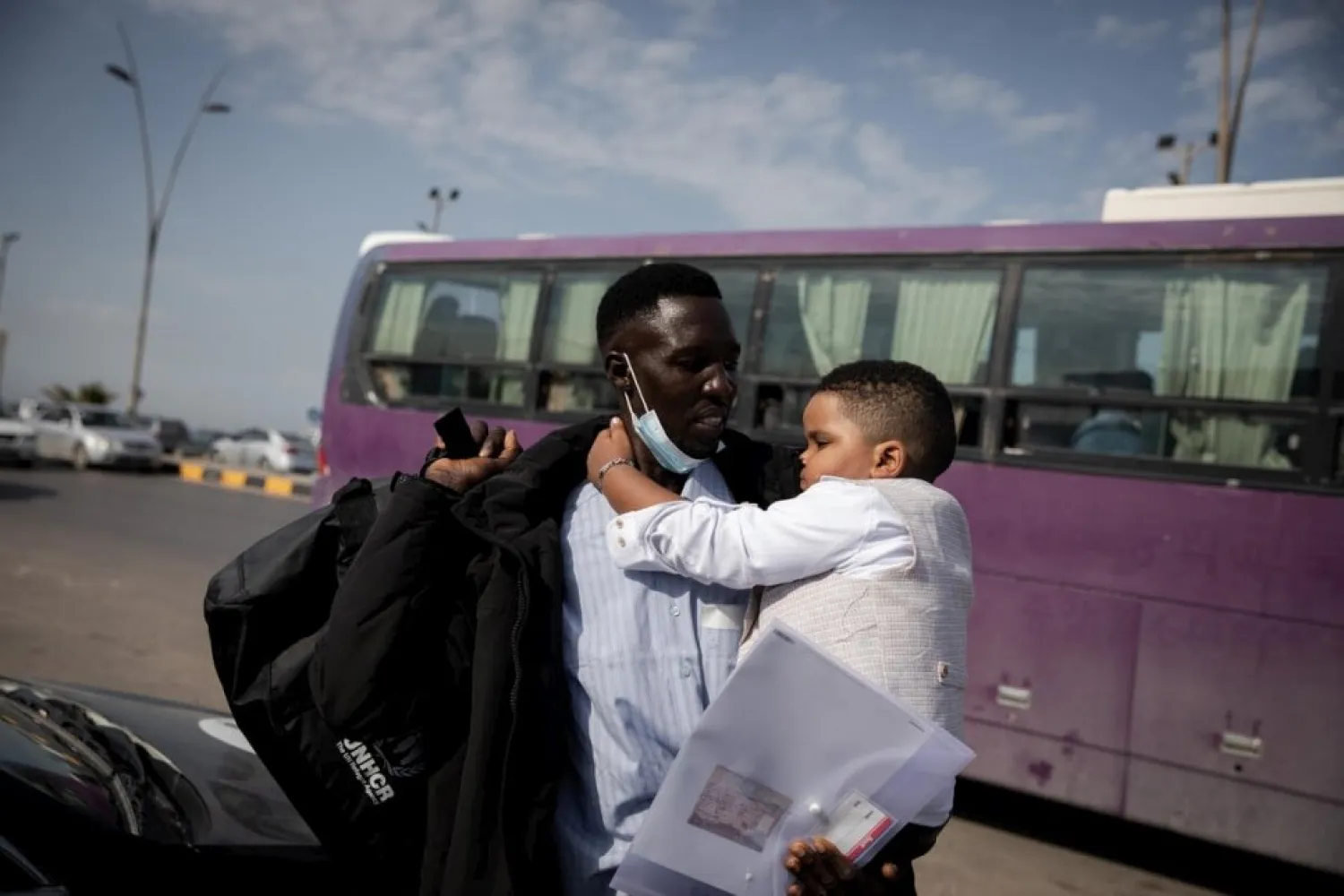 Sudanese refugee Osman helps carry fellow evacuee Hayat’s young son as they arrive at Tripoli airport to board a UNHCR-chartered flight to Rome. © UNHCR/Mohamed Alalem

