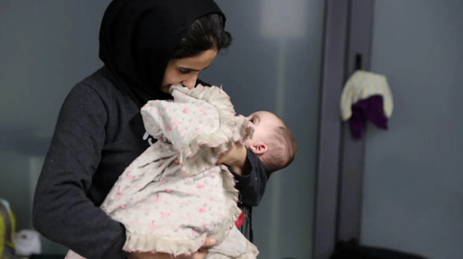 أم وطفلها في مطار مينسك قبل رحلة العودة إلى العراق أمس (رويترز)