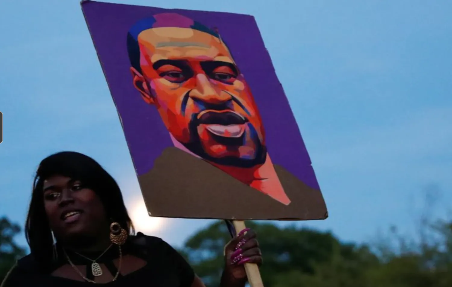 A woman holds a placard depicting George Floyd during a demonstration on the first anniversary of his death, in Brooklyn, New York City, New York, U.S., May 25, 2021. REUTERS/Shannon Stapleton