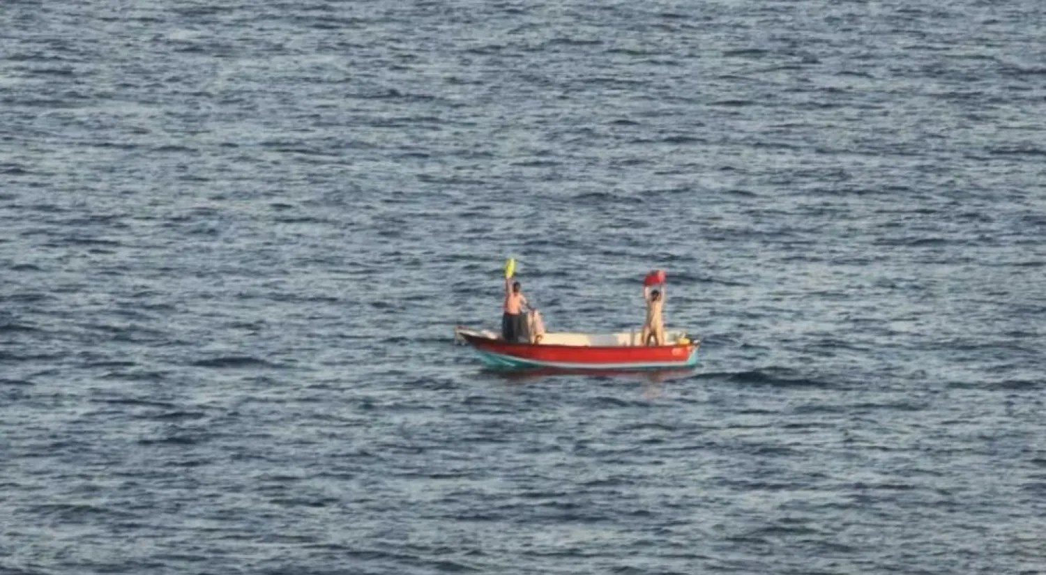 Two Iranian mariners signal for assistance after eight days adrift in Gulf waters before their rescue by the US Navy - US NAVY/AFP
