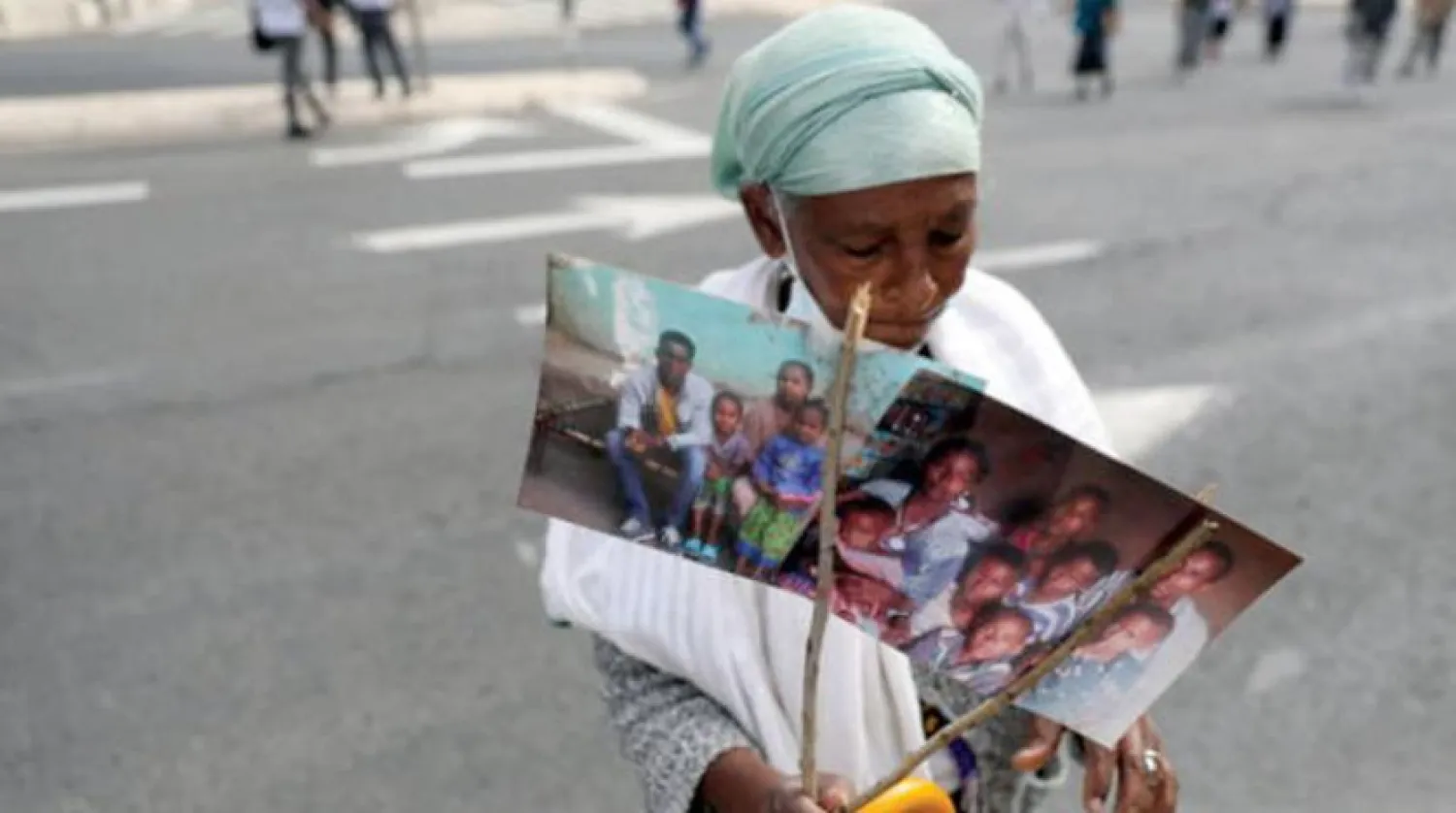 Yaşlı bir Falaşa Yahudisi, iki hafta önce İsrail hükümetine çağrıda bulunan bir protesto yürüyüşü sırasında hala Etiyopya’da olan akrabalarının fotoğraflarını tutuyor (EPA)