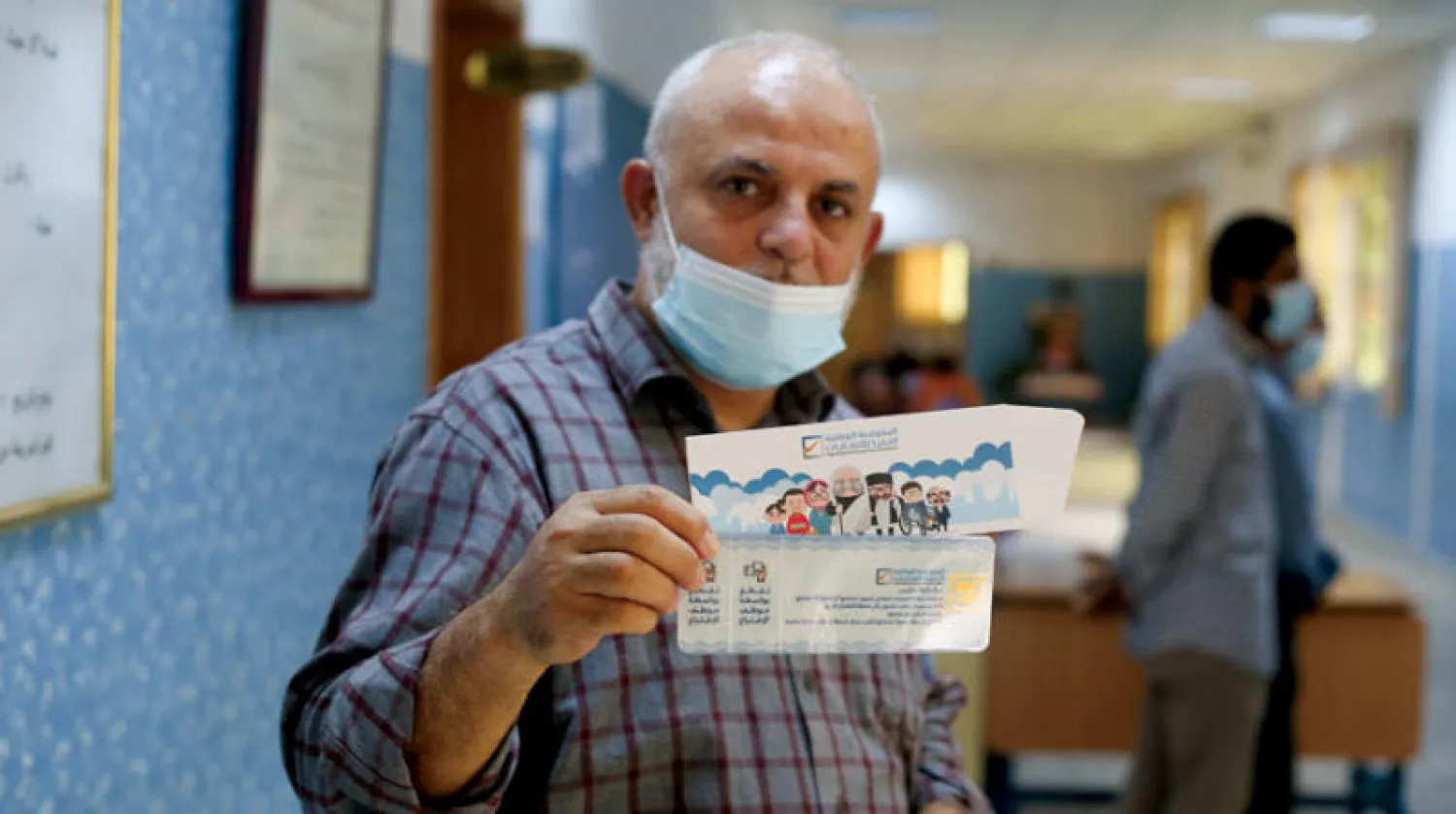 ليبي يُظهر بطاقة الناخب التي تلقاها في مركز اقتراع بطرابلس (رويترز)