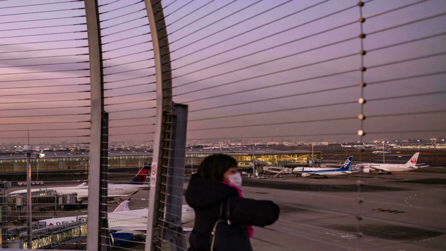 A woman looks on from the observation deck of Tokyo's Haneda international airport on November 29, 2021, as Japan announced plans to bar all new foreign travelers over the Omicron variant of Covid-19 Philip FONG AFP
