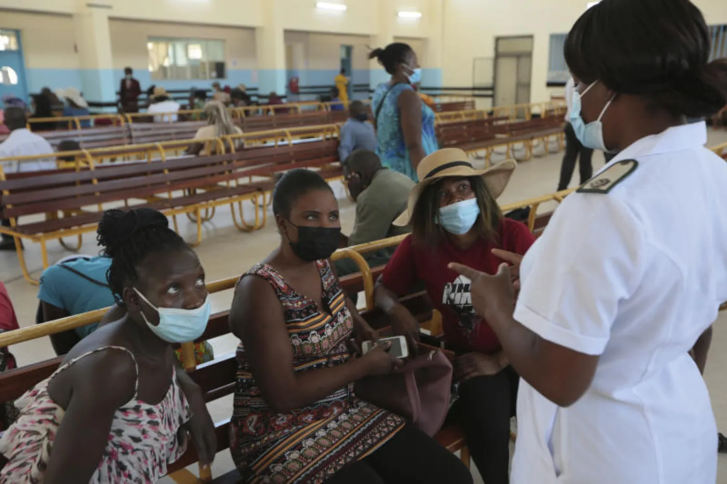 ممرضة تتحدث مع أشخاص ينتظرون التطعيم ضد فيروس «كورونا» بمستشفى عام في هراري (أ.ب)