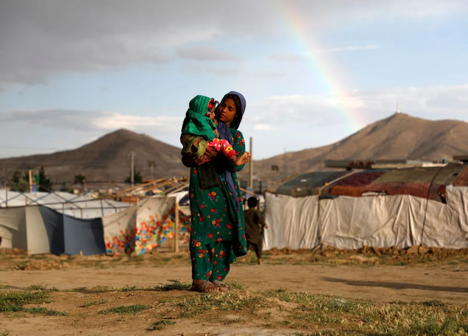 An internally displaced Afghan girl carries a child near their shelter at a refugee camp on the outskirts of Kabul, Afghanistan June 20, 2019. REUTERS/Stringer