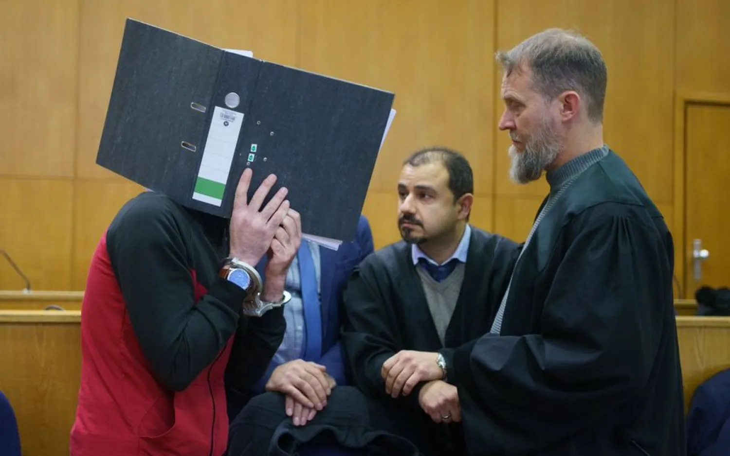 30 November 2021, Hessen, Frankfurt_Main: Iraqi defendant Taha Al-J. (L) covers his face with a folder as he enters the courtroom of the Frankfurt's Higher Regional Court before a verdict is pronounced. Photo: Frank Rumpenhorst/dpa-Pool/dpa