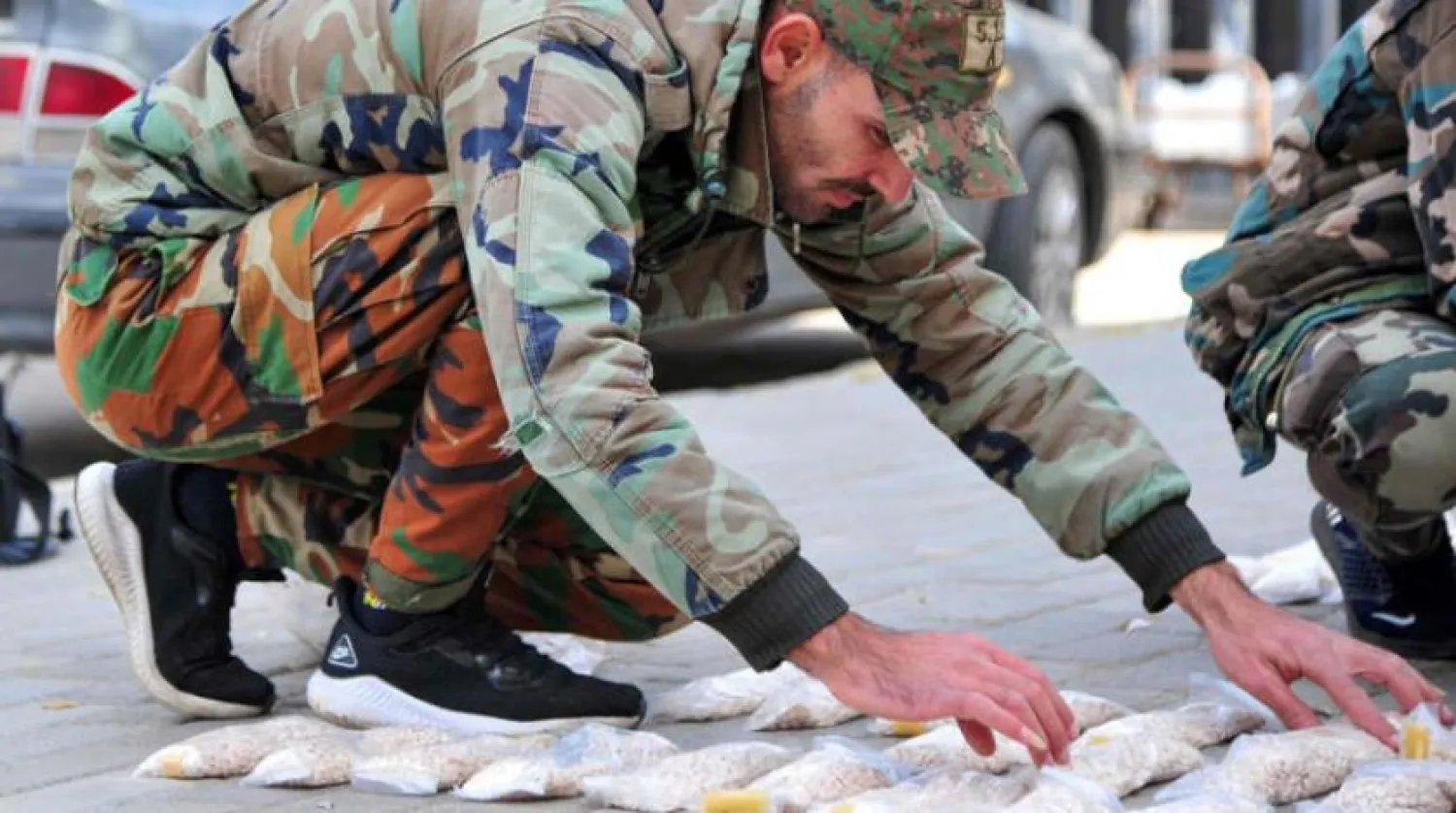  Two members of the Syrian security forces near the “Captagon” shipment seized in Damascus (AFP)