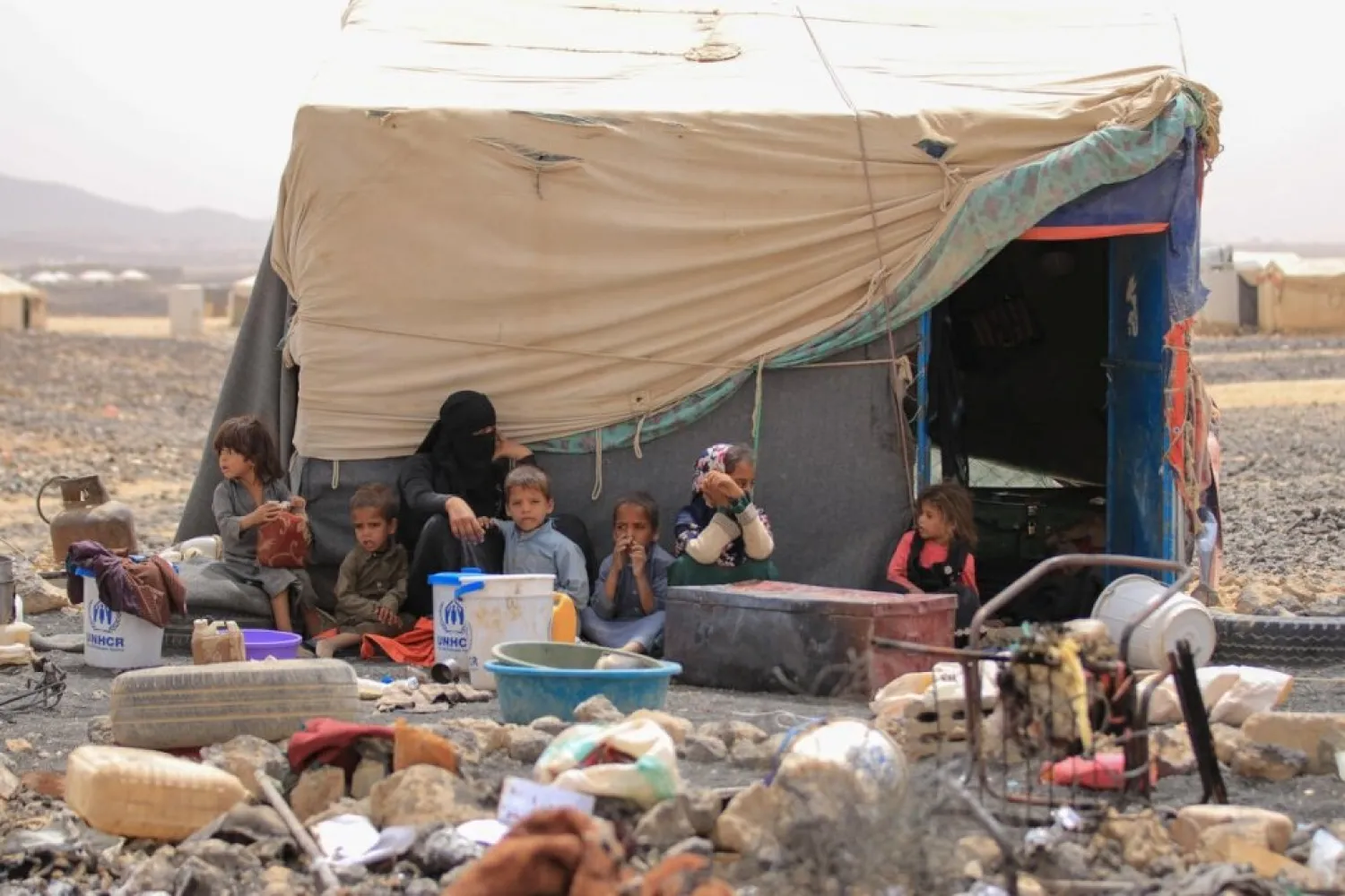 An internally displaced Yemeni family sit outside their shelter at Al-Suwaidan camp in Marib city, Yemen, June 2021. UNHCR/Jihad Al-Nahari 