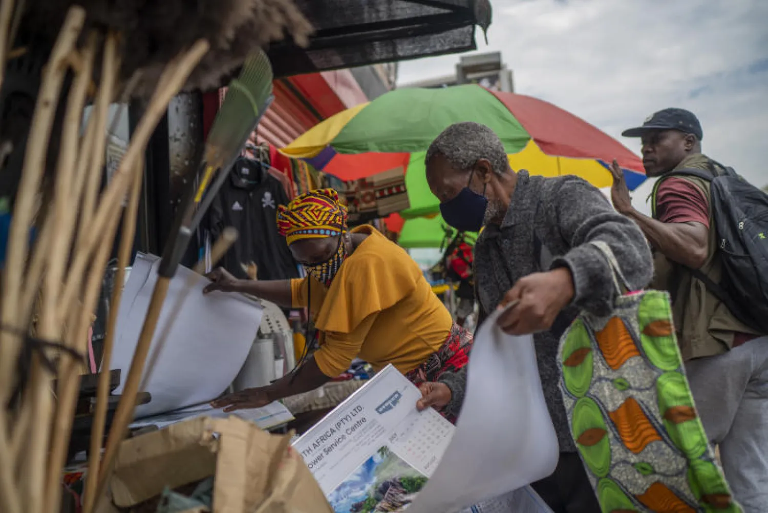 زوجان يرتديان قناعين واقيين خلال التسوق في إحدى الأسواق الخارجية بجنوب أفريقيا (أ.ب)