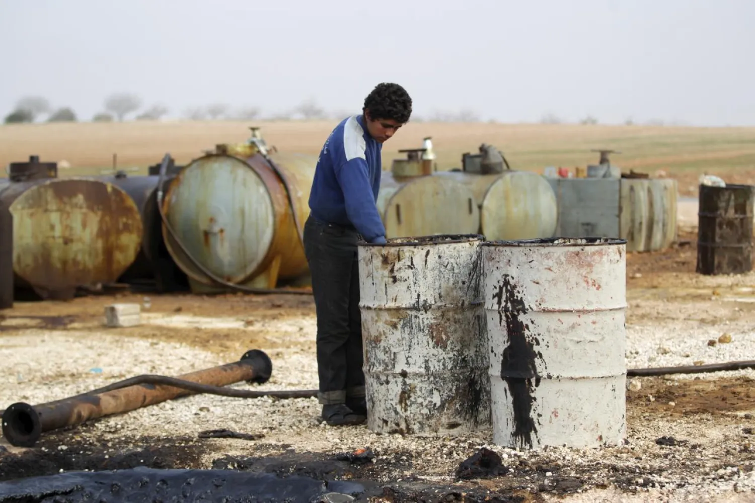 FILE PHOTO: A youth works at a makeshift oil refinery site in Marchmarin town, southern countryside of Idlib, Syria December 16, 2015. REUTERS/Khalil Ashawi