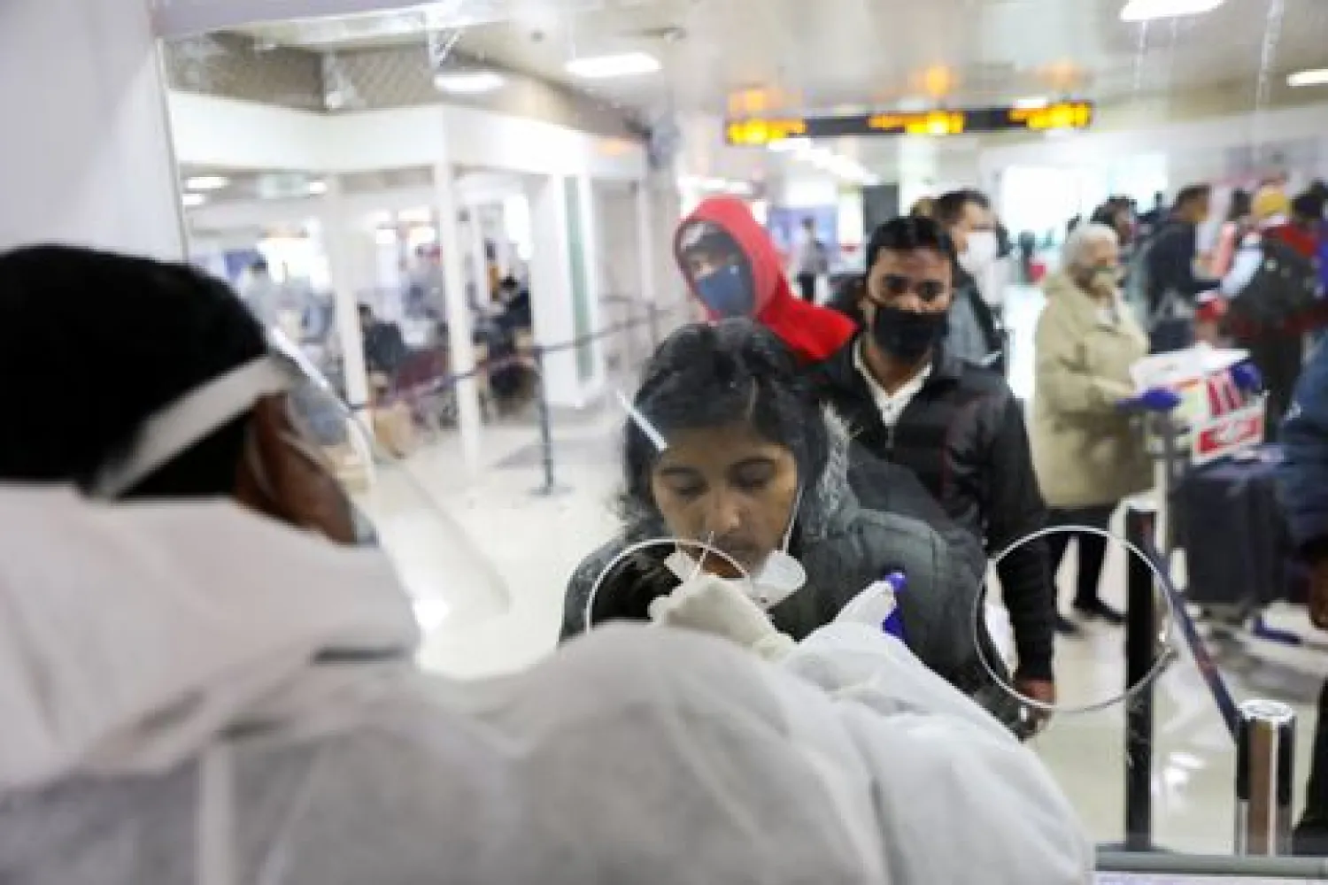 A healthcare worker collects a coronavirus disease (COVID-19) test swab sample from a woman at the Indira Gandhi International Airport in New Delhi, India, December 3, 2021. REUTERS/Anushree Fadnavis


