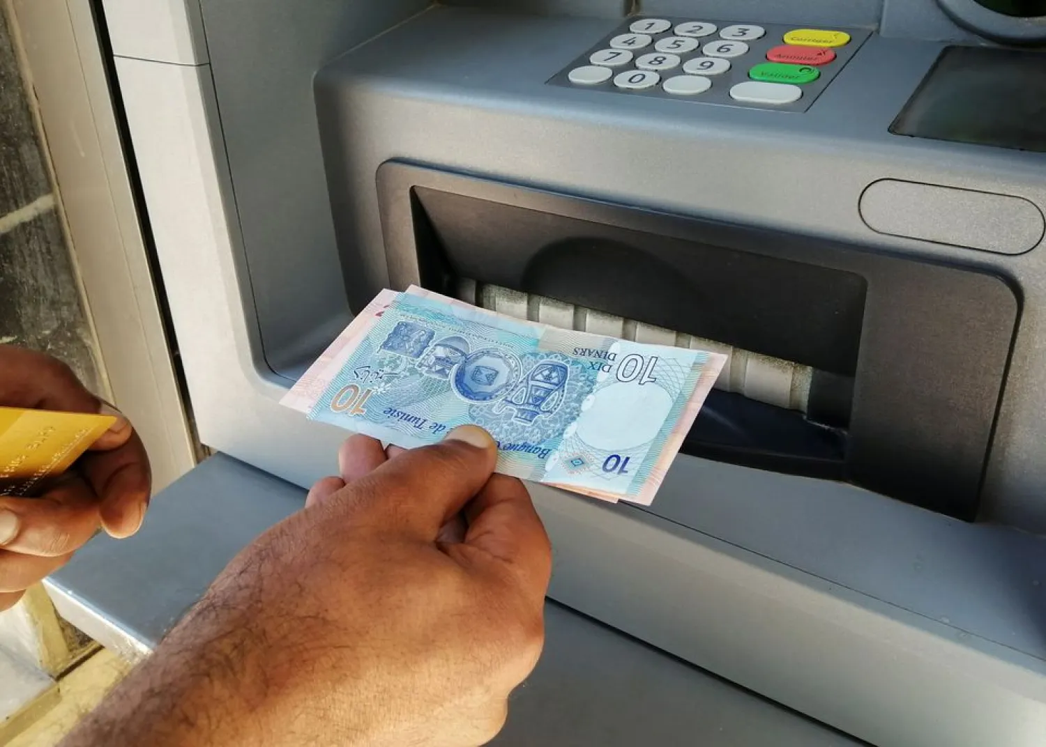 A man displays Tunisian dinar banknotes after withdrawing cash from an ATM machine in Tunis, Tunisia, May 25, 2021. Picture taken May 25, 2021. (Reuters)