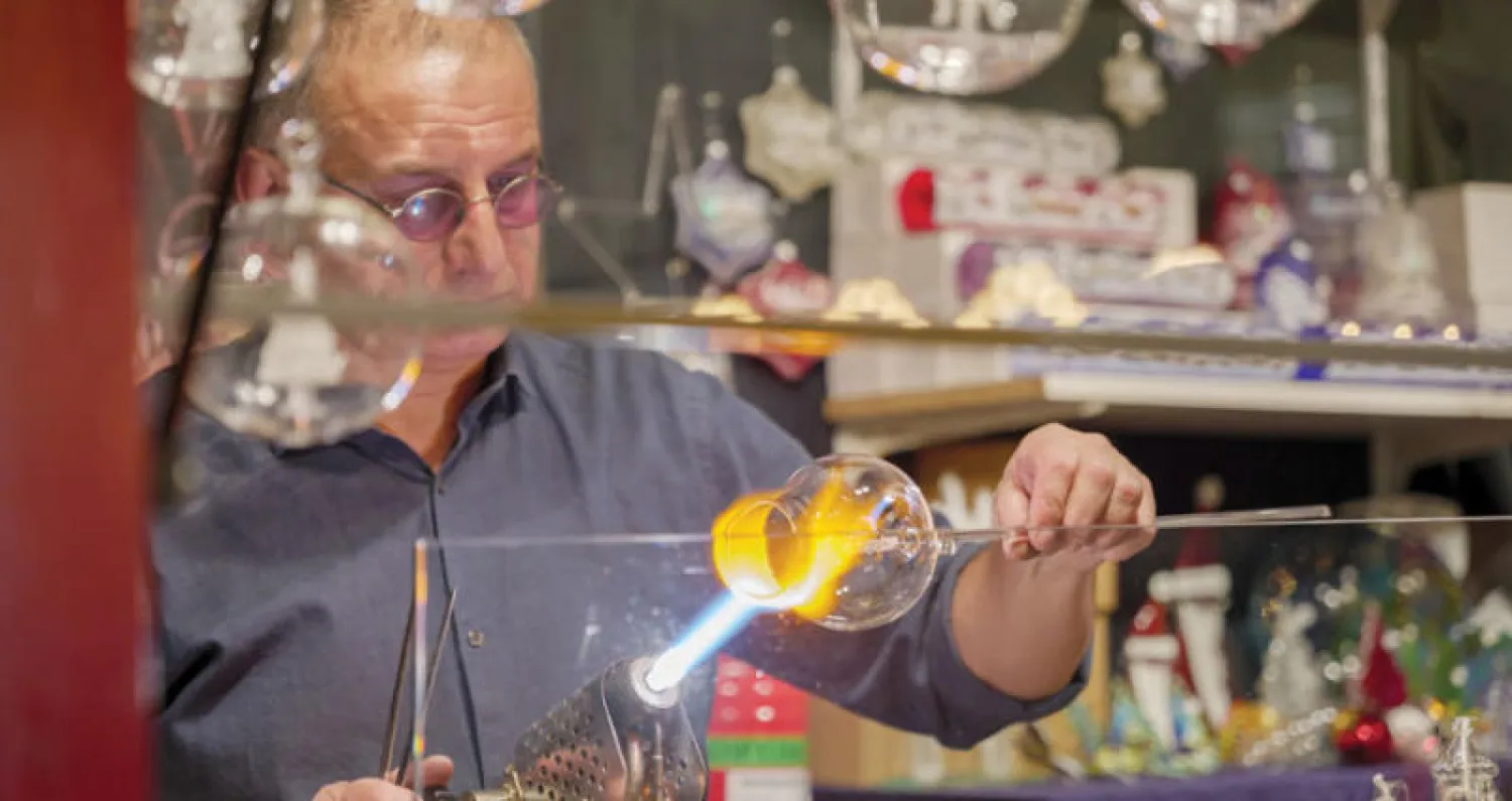 صانع زجاج خلال انتاج قطعة لزينة شجرة الميلاد في ألمانيا