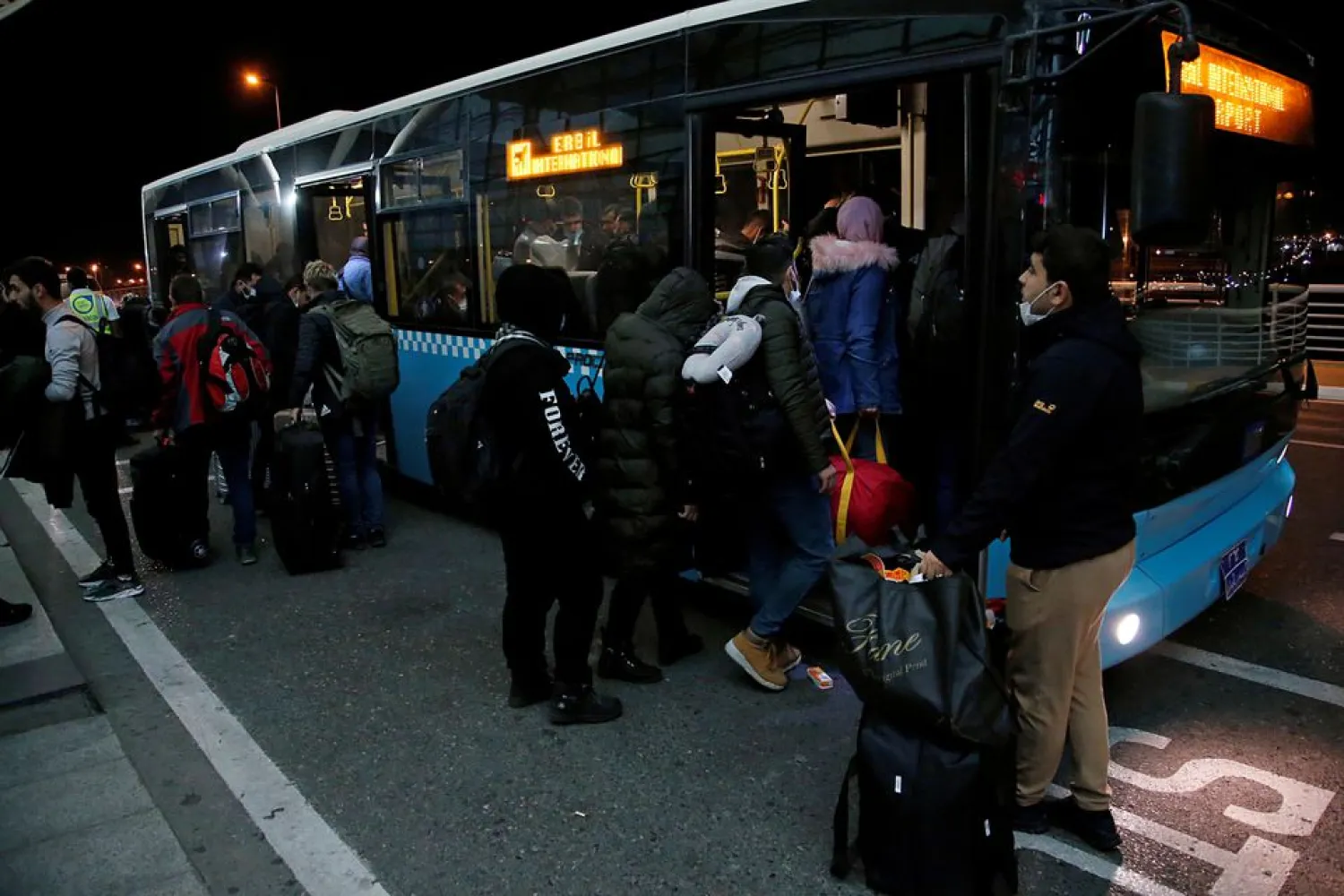 Iraqi migrants, who voluntarily registered for an evacuation flight from Belarus, board a bus upon arriving at Erbil International Airport, in Erbil, Iraq, November 26, 2021. (Reuters)