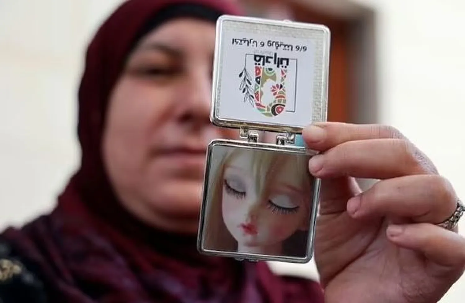 A candidate for Palestinian council elections shows a pocket mirror included in campaign merchandise that an all-woman list is offering as part of their distinctly feminine campaign merchandise - AFP