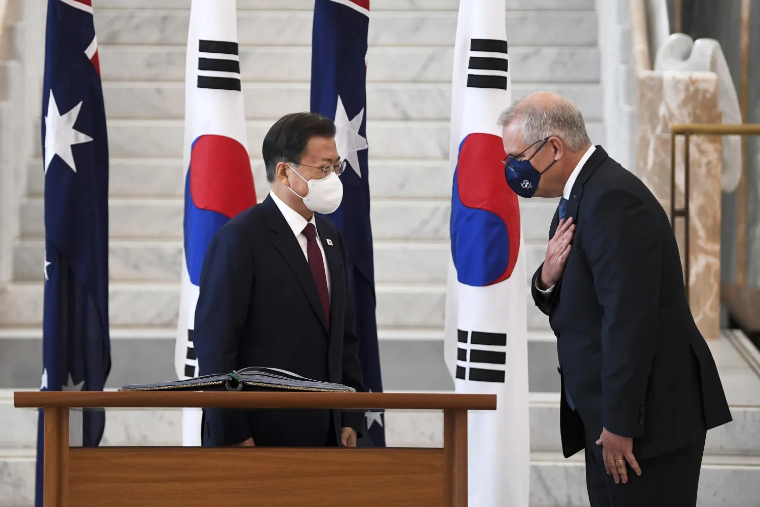 South Korean President Moon Jae-in, left, is invited to sign a visitor's book by Australian Prime Minister Scott Morrison at Parliament House, in Canberra, Australia, Monday, Dec. 13, 2021.(Lukas Coch/Pool Photo via AP)

