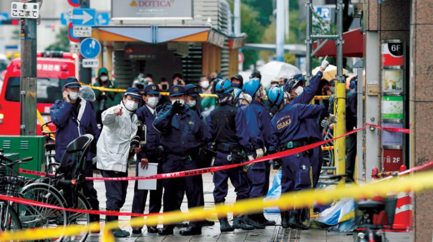 رجال الإطفاء والشرطة أمام المبنى المحترق في أوساكا ثاني أكبر مدن اليابان (أ.ب)