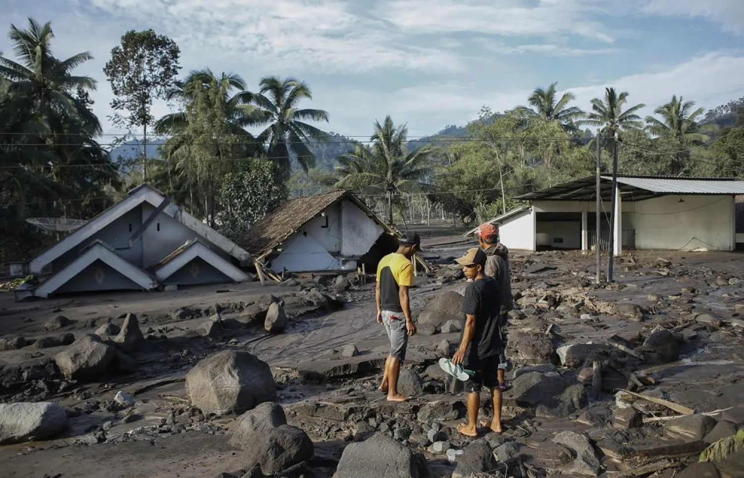 Villagers view homes buried under volcanic materials from the eruption of Mount Semeru in Lumajang, East Java, Indonesia, Thursday, Dec. 9 ,2021. The 3,676-meter (12,060-foot) volcano erupted on Saturday killing dozens of people and left thousands others homeless. (AP Photo/Bibni)
