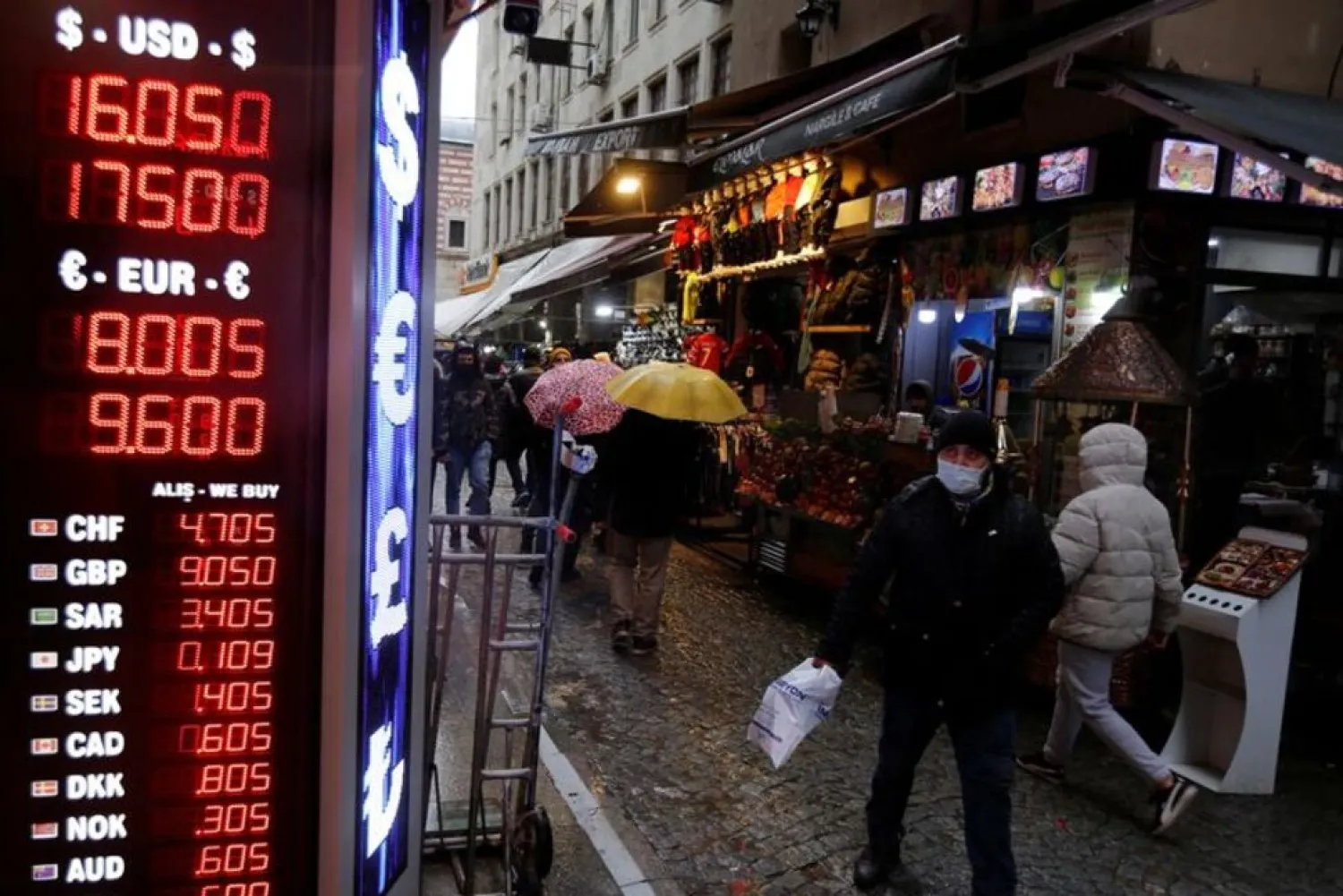 People walk past a board showing the currency exchange rates outside an exchange office in Istanbul, Turkey December 17, 2021. (Reuters)