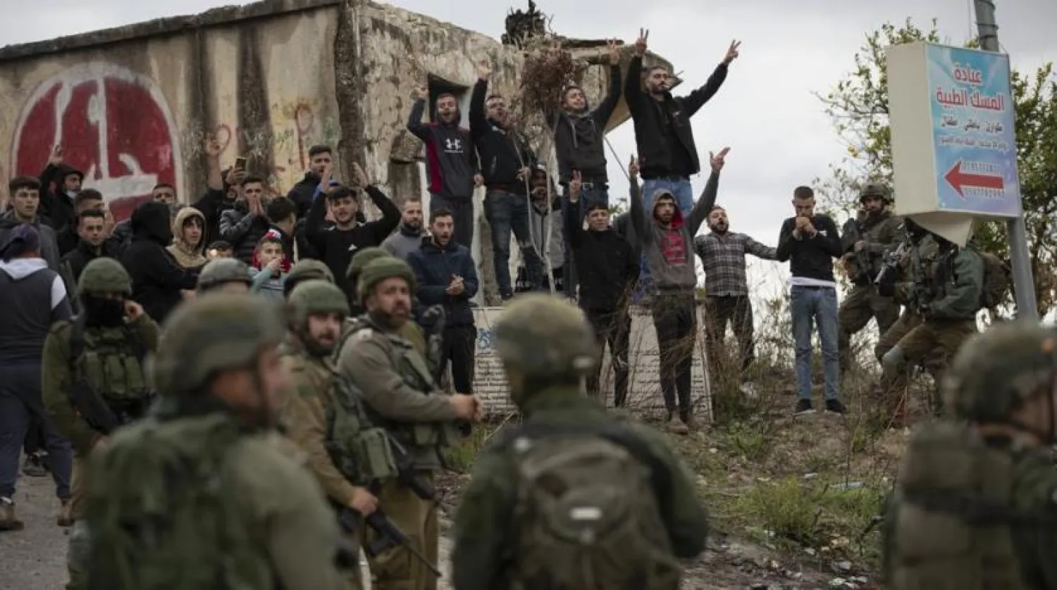 Israeli soldiers stand between Palestinians and a Jewish settler following a settler attack on the West Bank village of Burqa, Friday, Dec. 17, 2021. (AP Photo/Majdi Mohammed)
