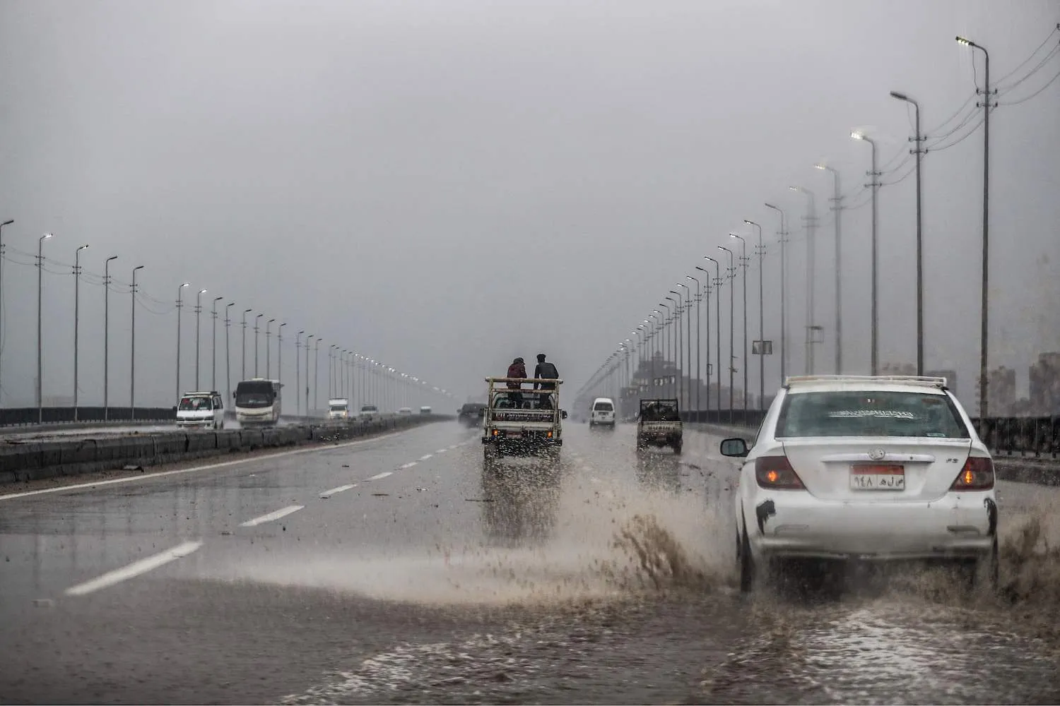 Vehicles drive along a flooded portion of the ring-road highway that encircles the Egyptian capital Cairo and it's twin city of Giza, in Giza on Mar. 12, 2020, amdist a heavy rain storm. (AFP)