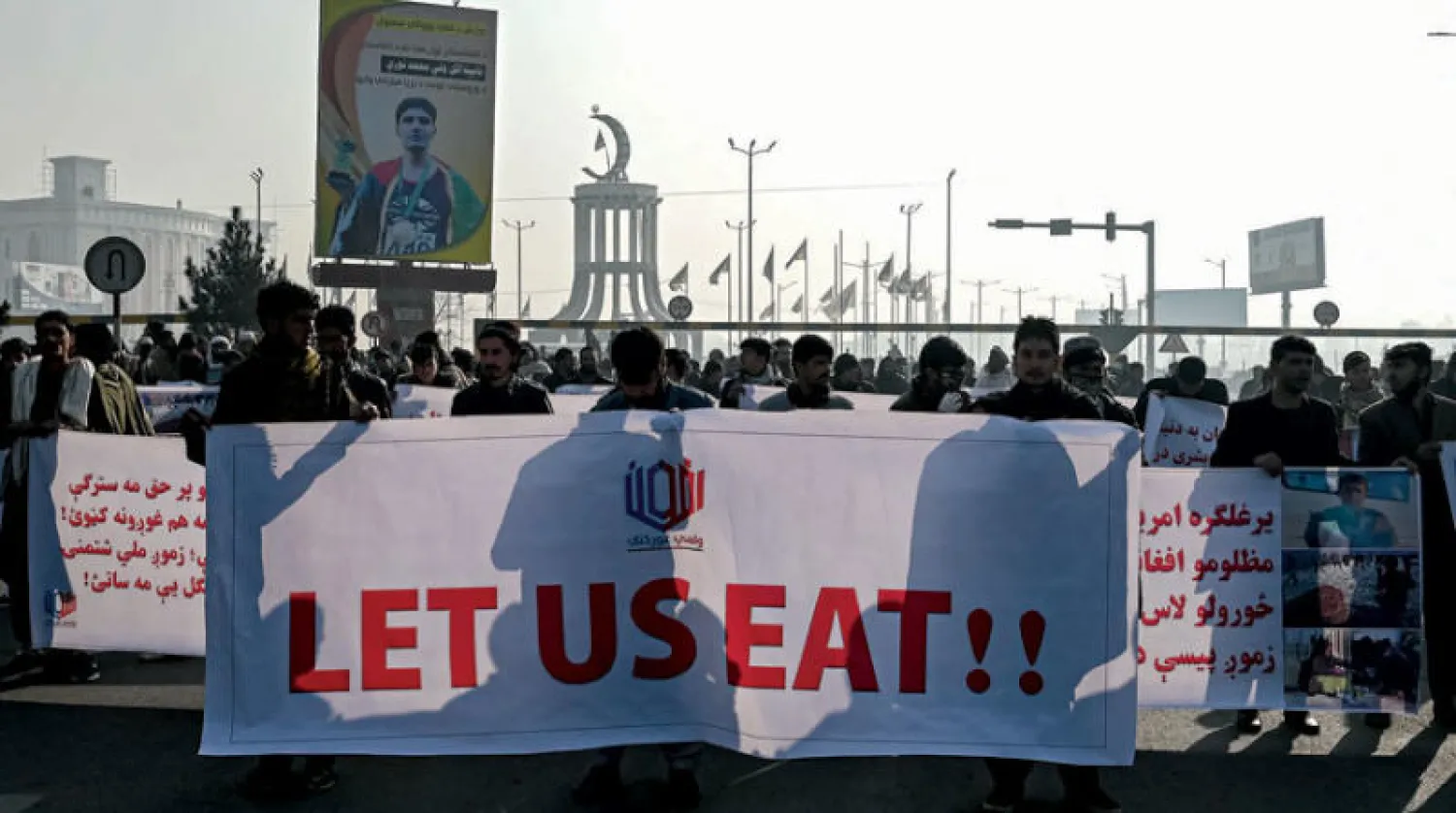 أفغان يرفعون لافتة كتب عليها «دعونا نأكل» خلال مسيرة في كابل أمس (أ.ف.ب)