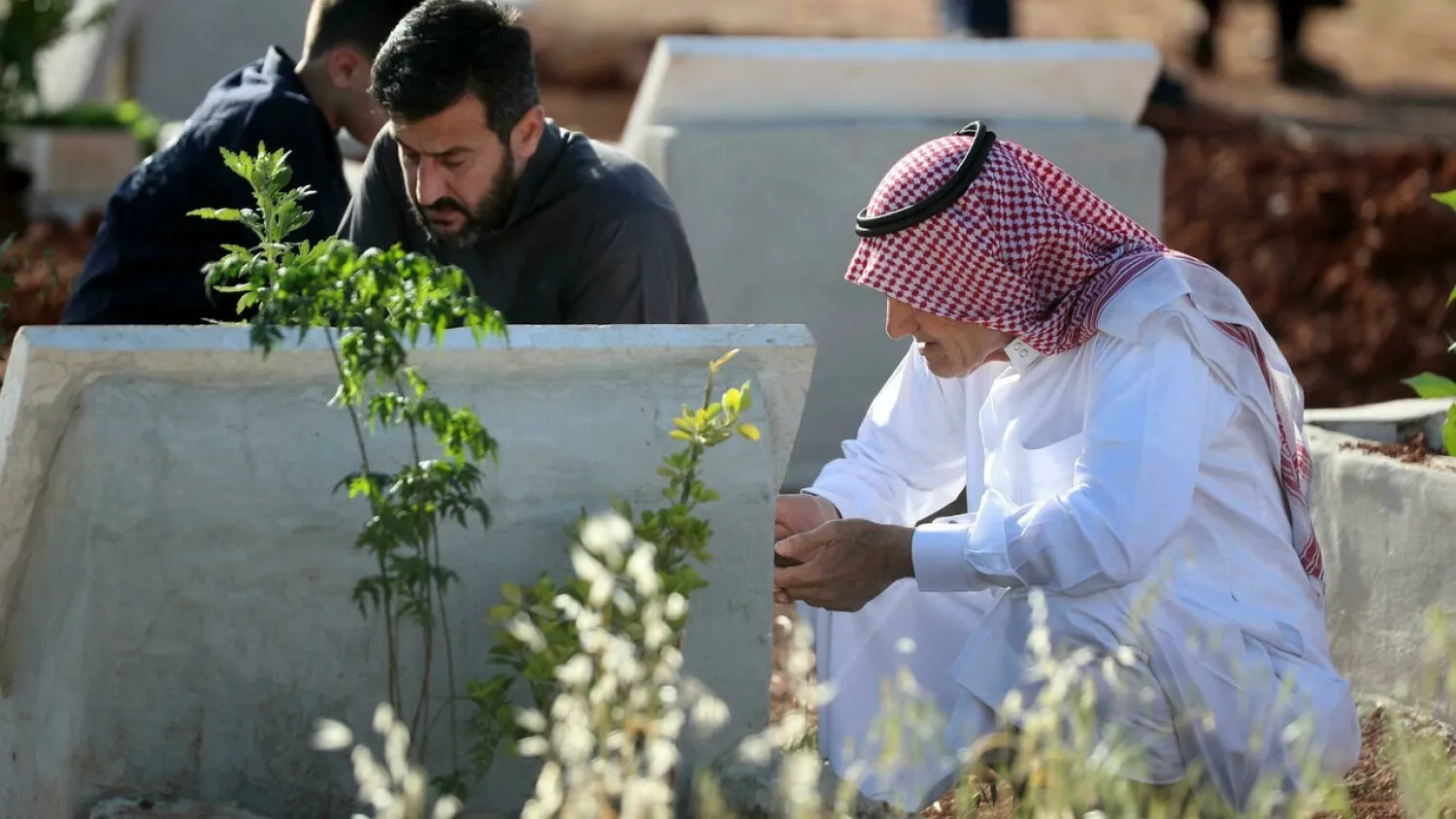 Syrian families visit the graves of loved ones in Binnish in the opposition-held northwestern region of Idlib in May. (AFP)