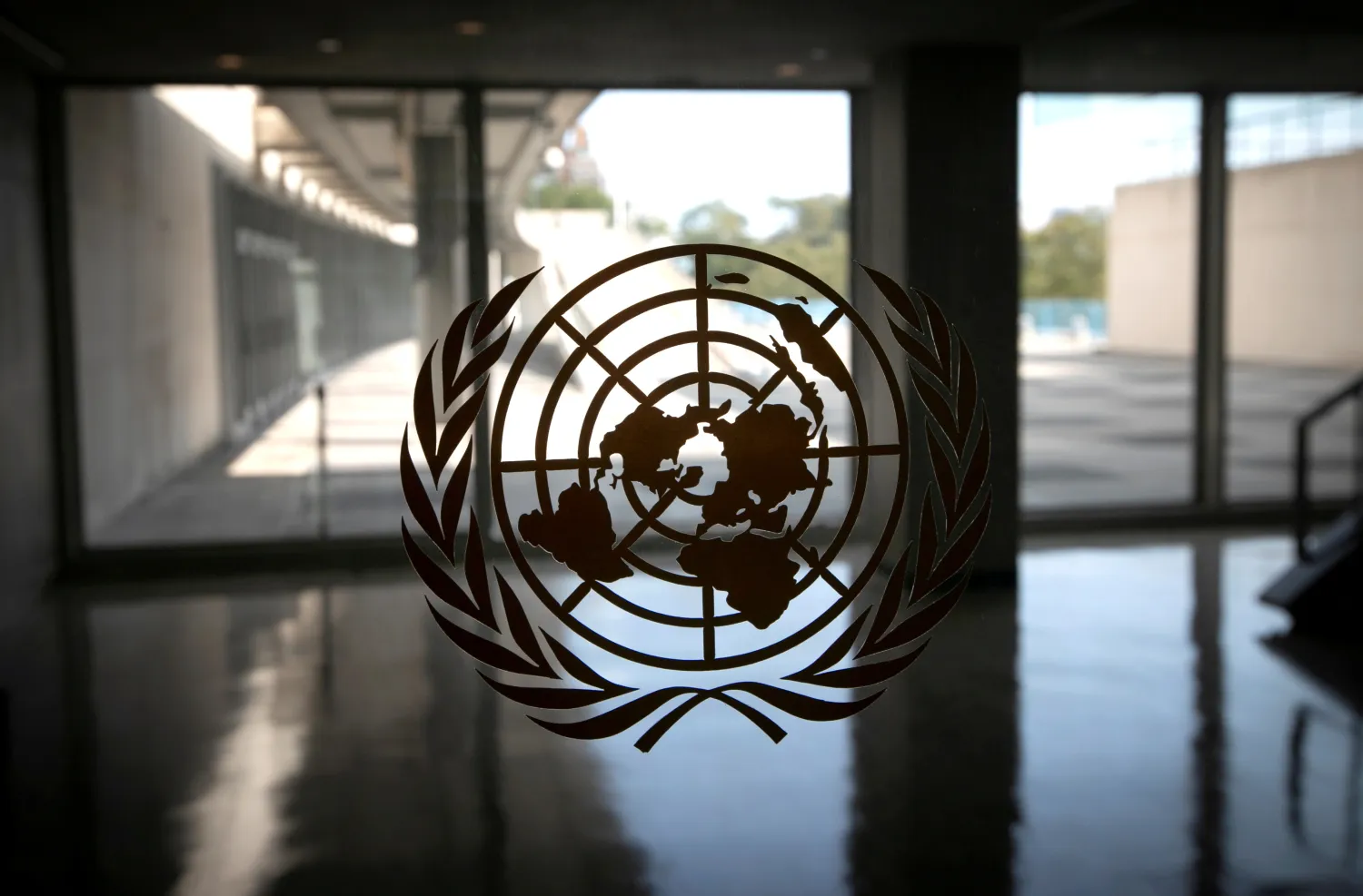 The United Nations logo is seen on a window in an empty hallway at United Nations headquarters in New York, US, September 21, 2020. REUTERS/Mike Segar/File Photo