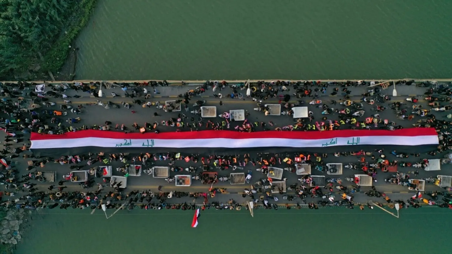 An aerial view of Iraqis, carrying posters of anti-government protesters killed in 2019, at a march on the Zeitoun bridge in Iraq's southern city of Nasiriyah on November 28, 2021. (AFP)