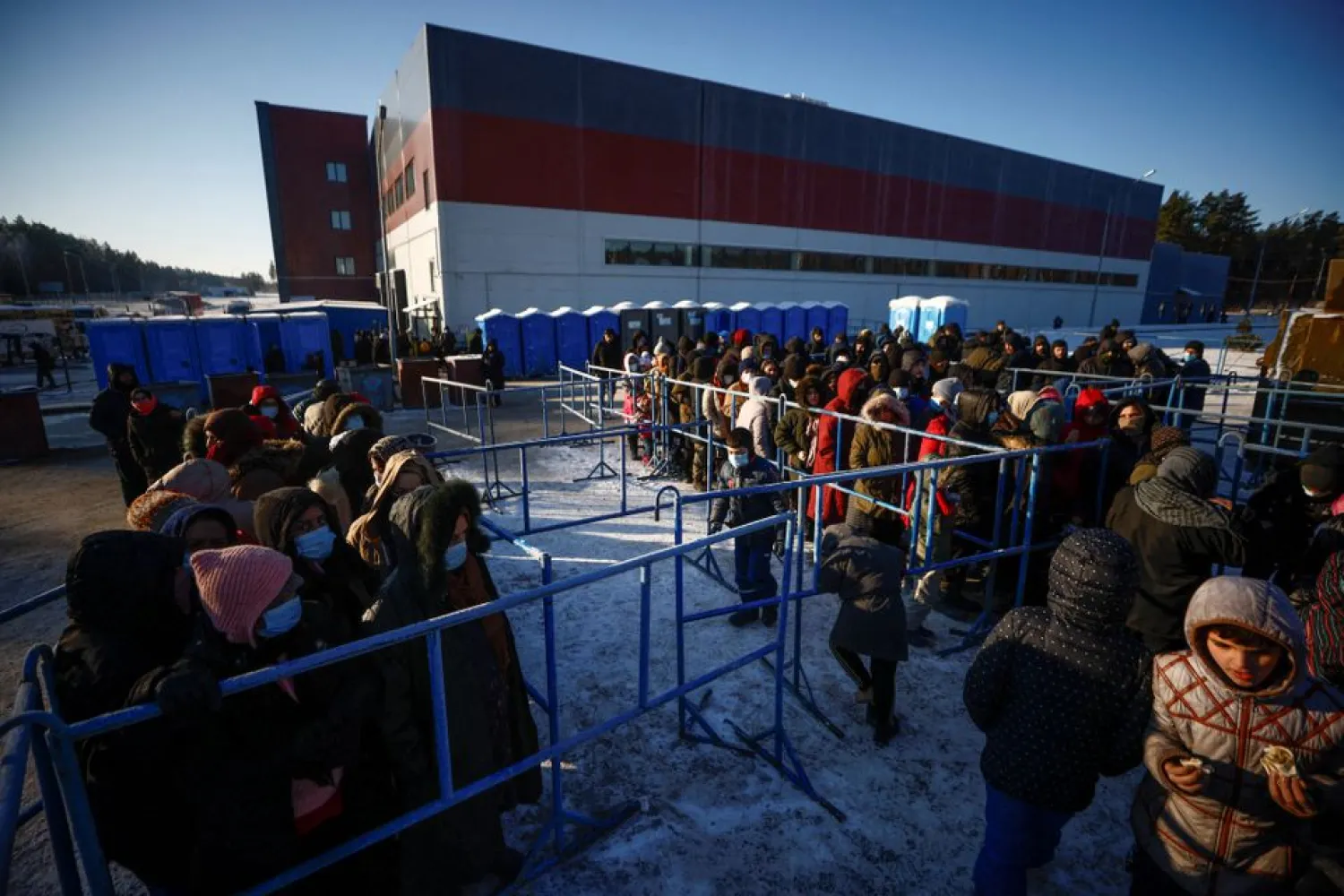 Migrants queue to receive meals outside the transport and logistics centre Bruzgi on the Belarusian-Polish border, in the Grodno region, Belarus December 22, 2021. REUTERS/Maxim Shemetov

