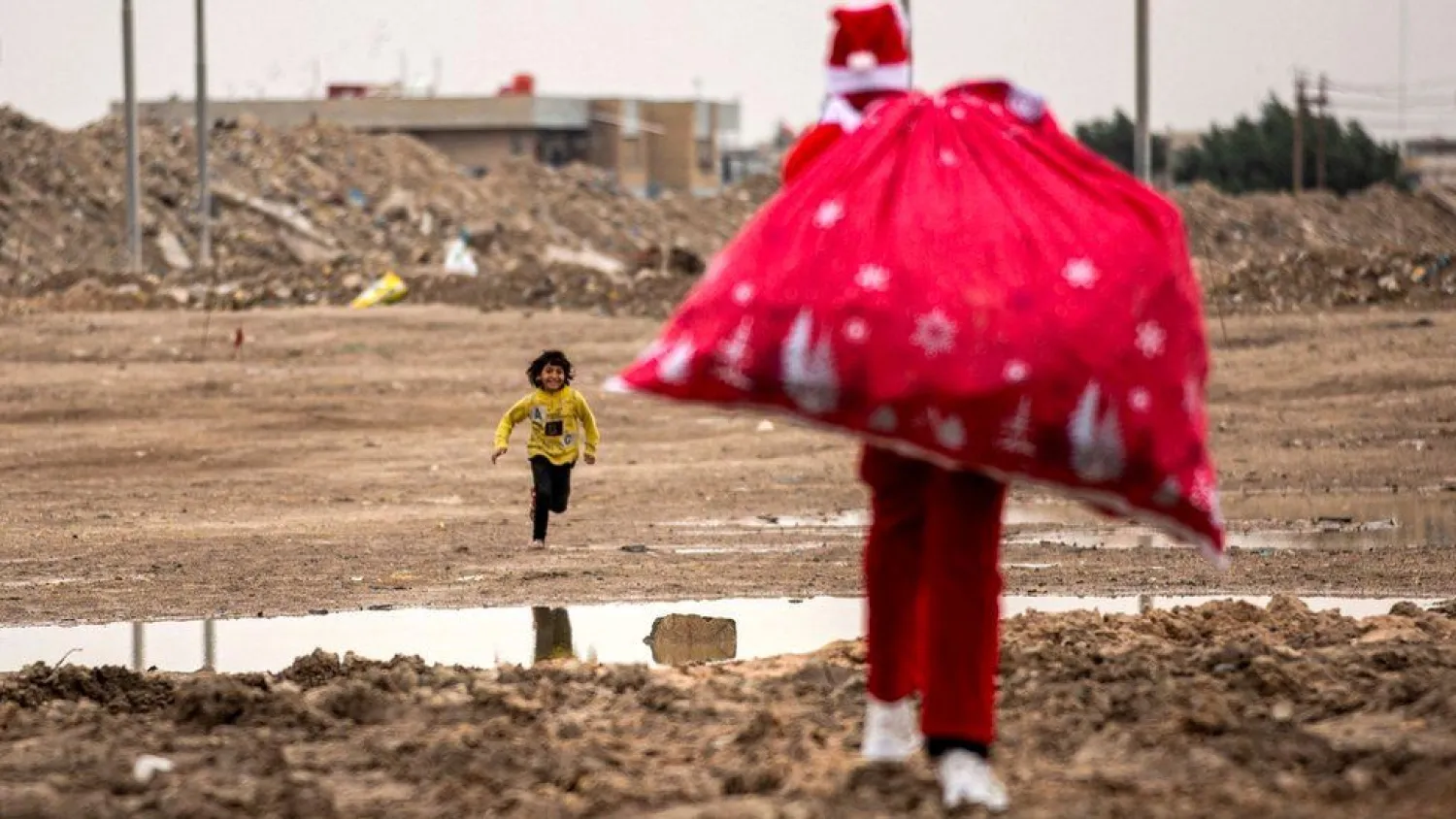 Dressed as Santa, Mohamed Maarouf distributes gifts to children in a slum near the center of Iraq's southern city of Basra. (AFP)